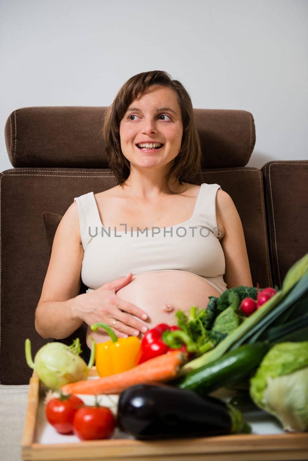 Lifestyle portrait of pregnant woman with vegetables in home kitchen