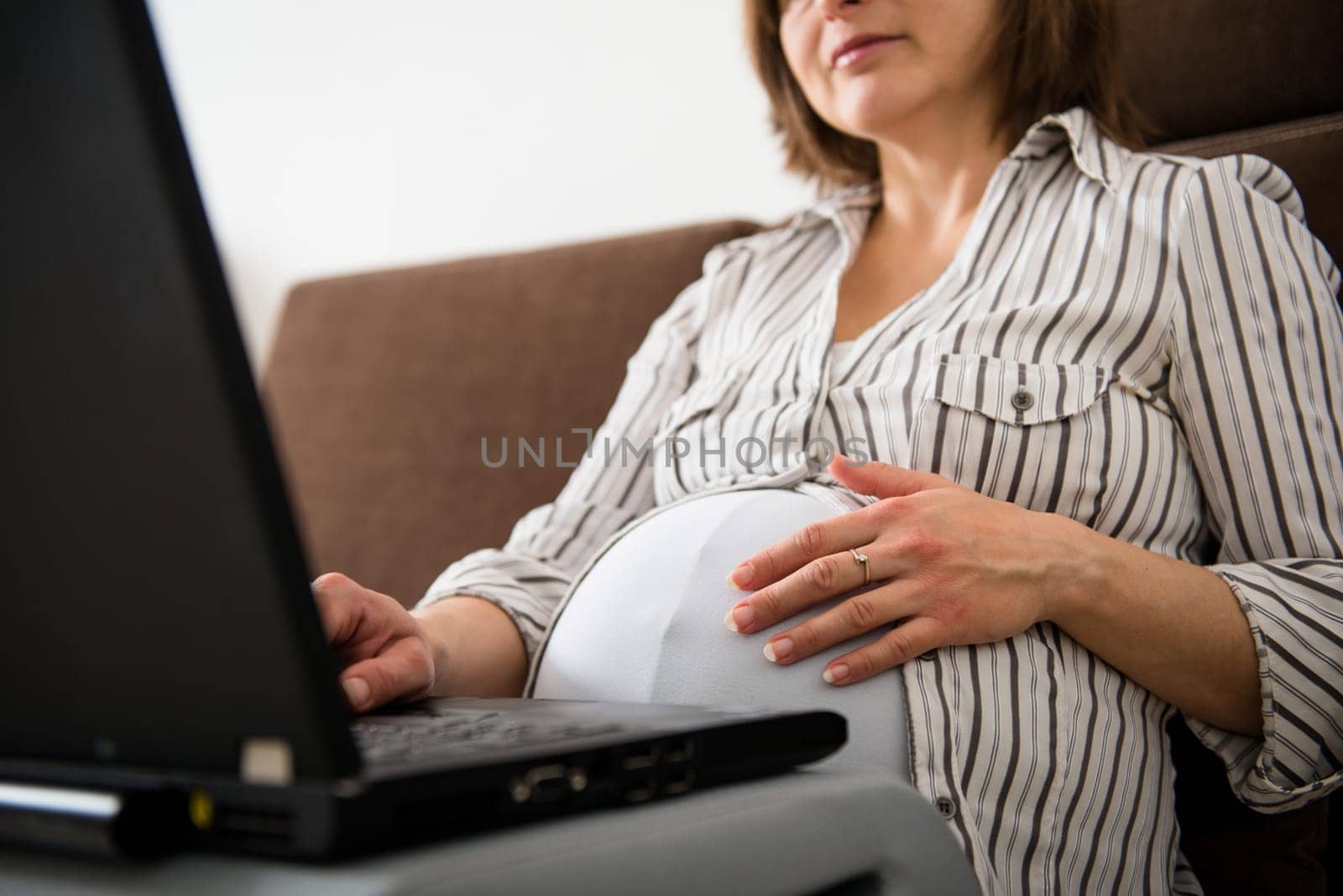 Torso of pregnant woman working on computer - home office