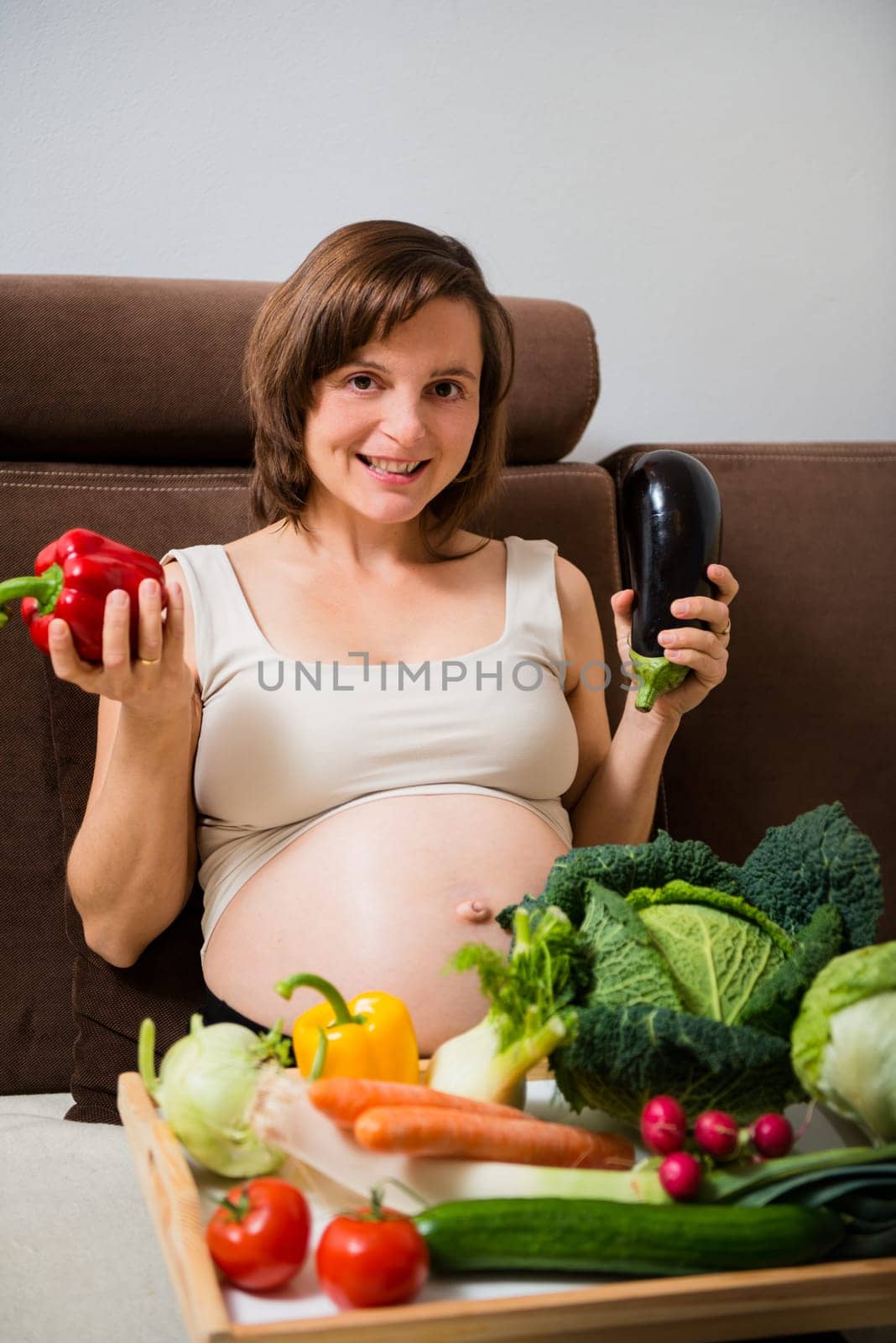 Lifestyle portrait of pregnant woman with vegetables in home kitchen