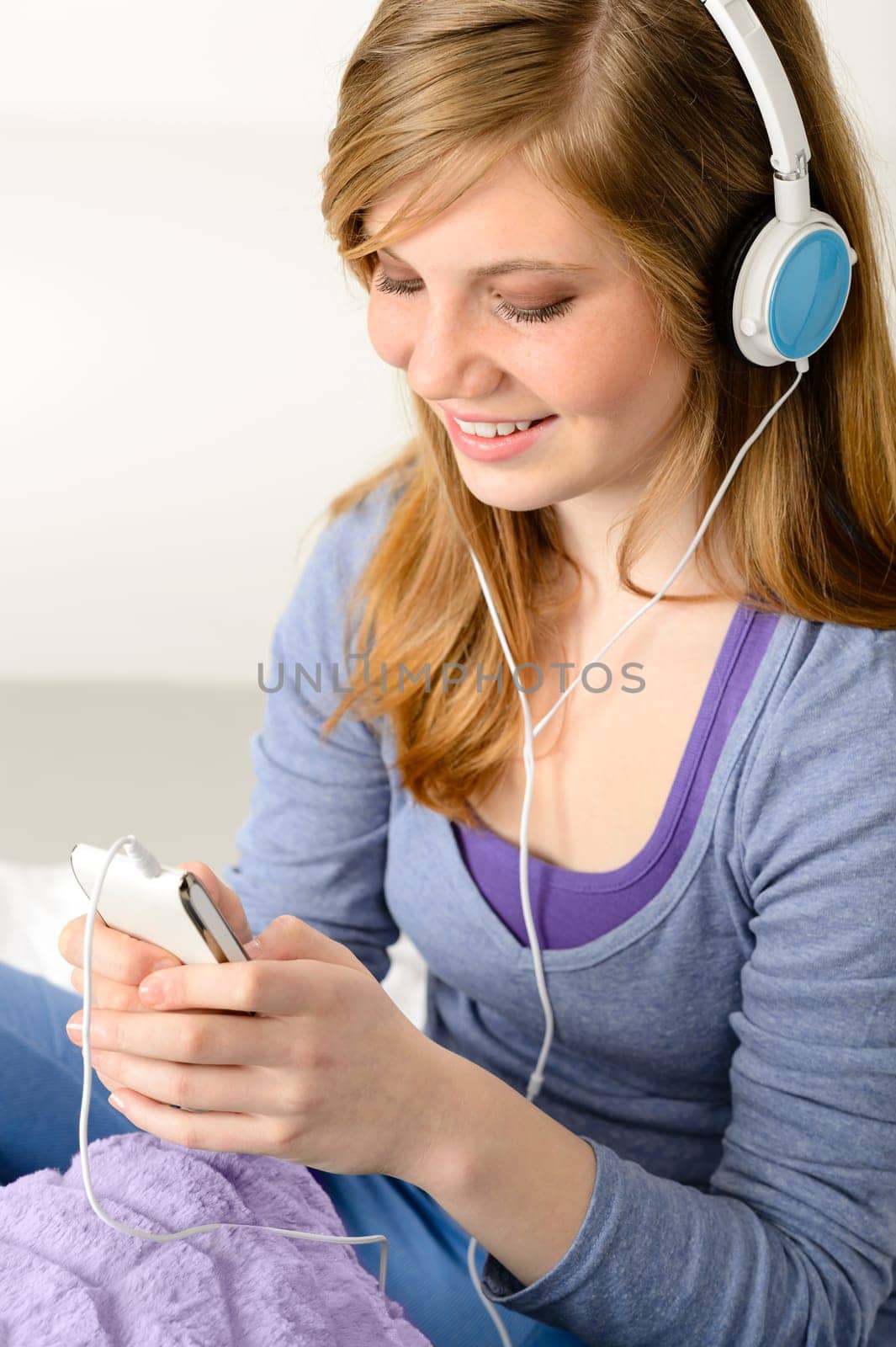 Pretty teenage girl listening to music using headphones