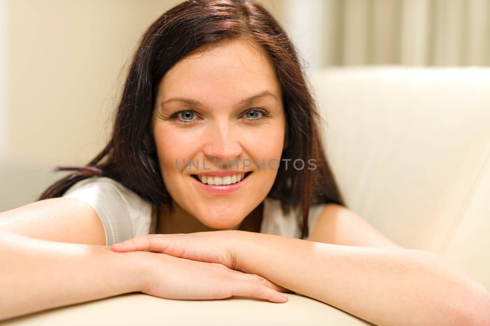 Smiling cheerful woman lying on couch looking at camera