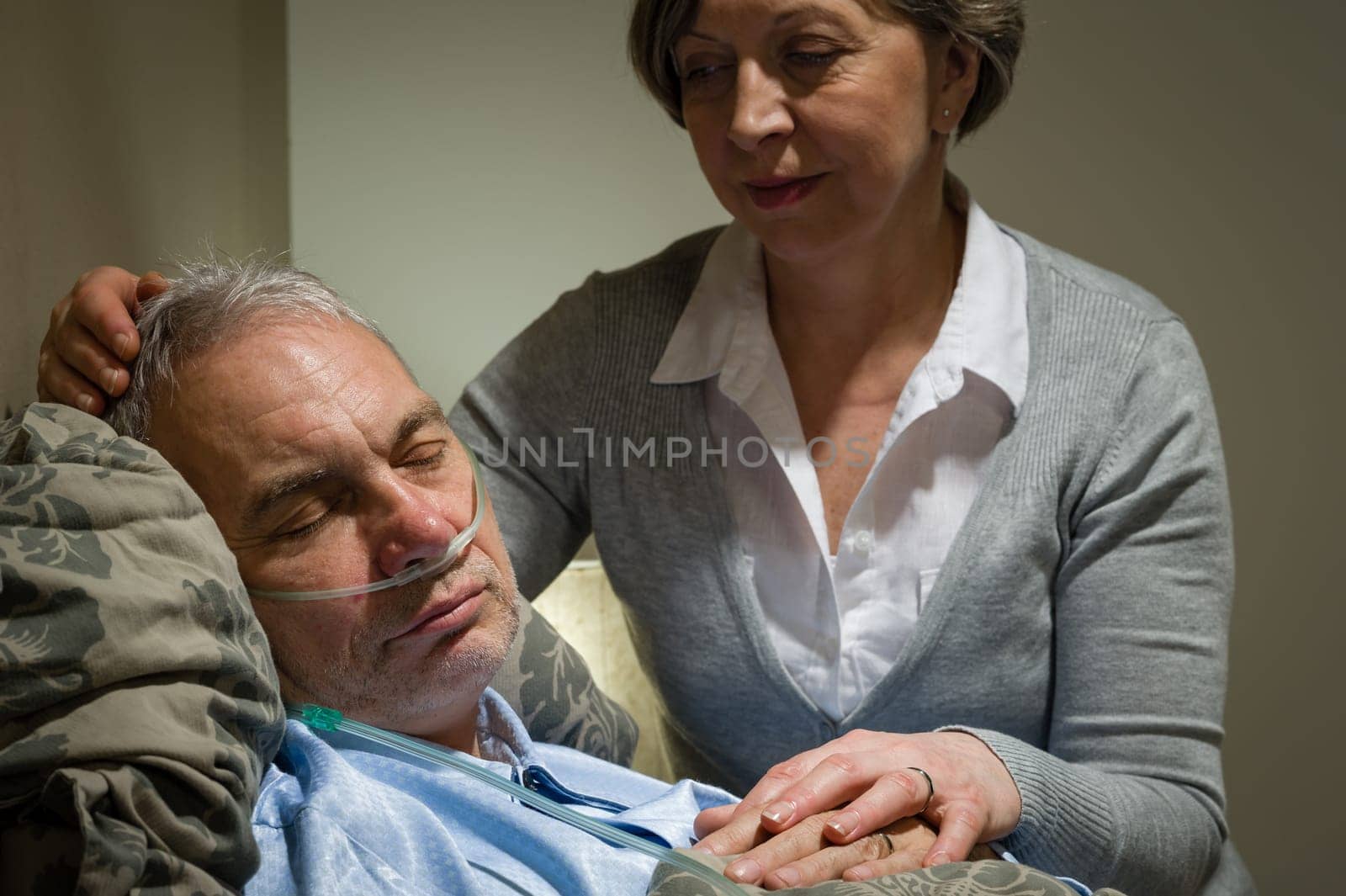 Caring female nurse with sleeping senior male patient