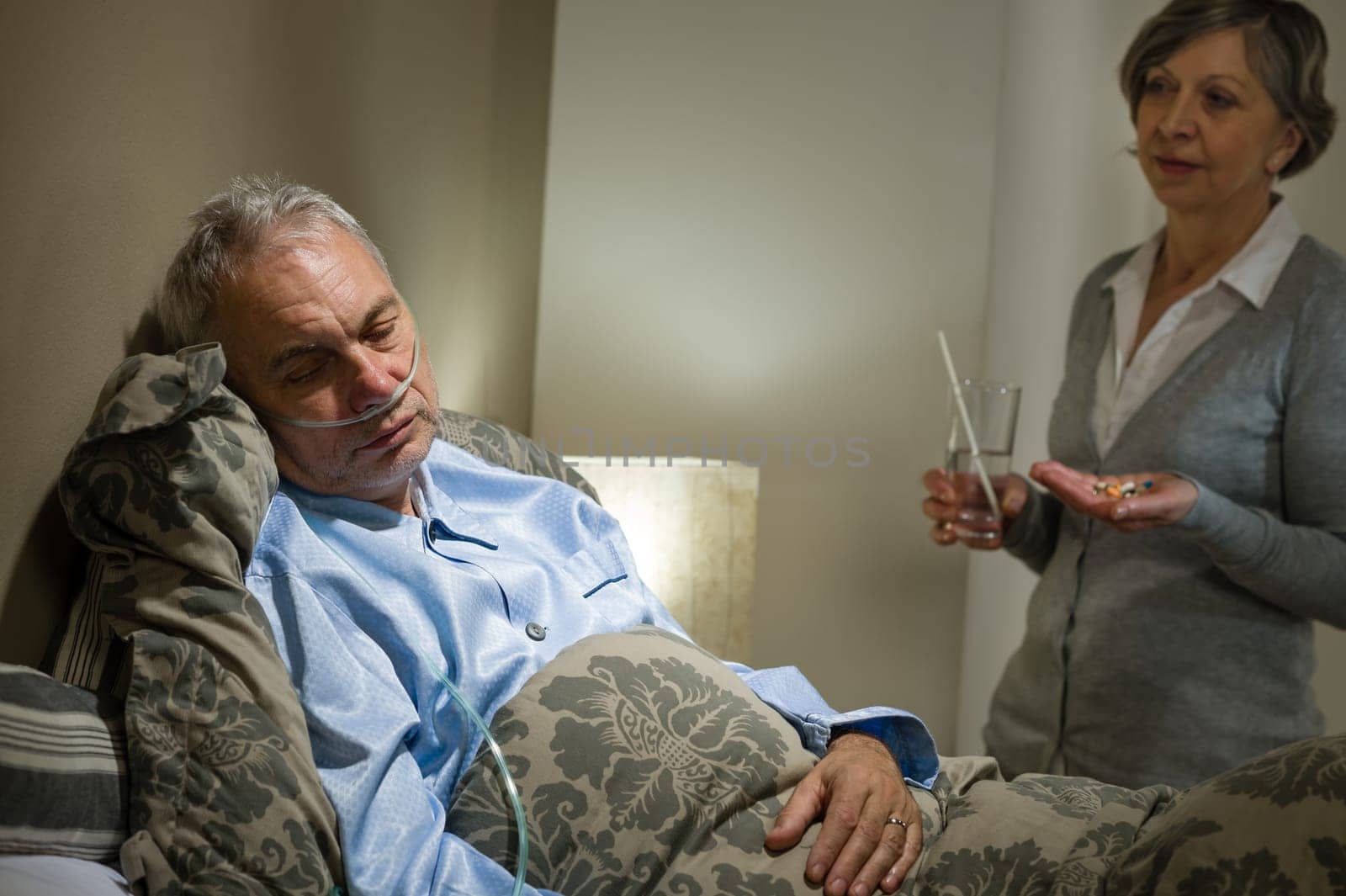 Ill old male patient and caring wife holding pills