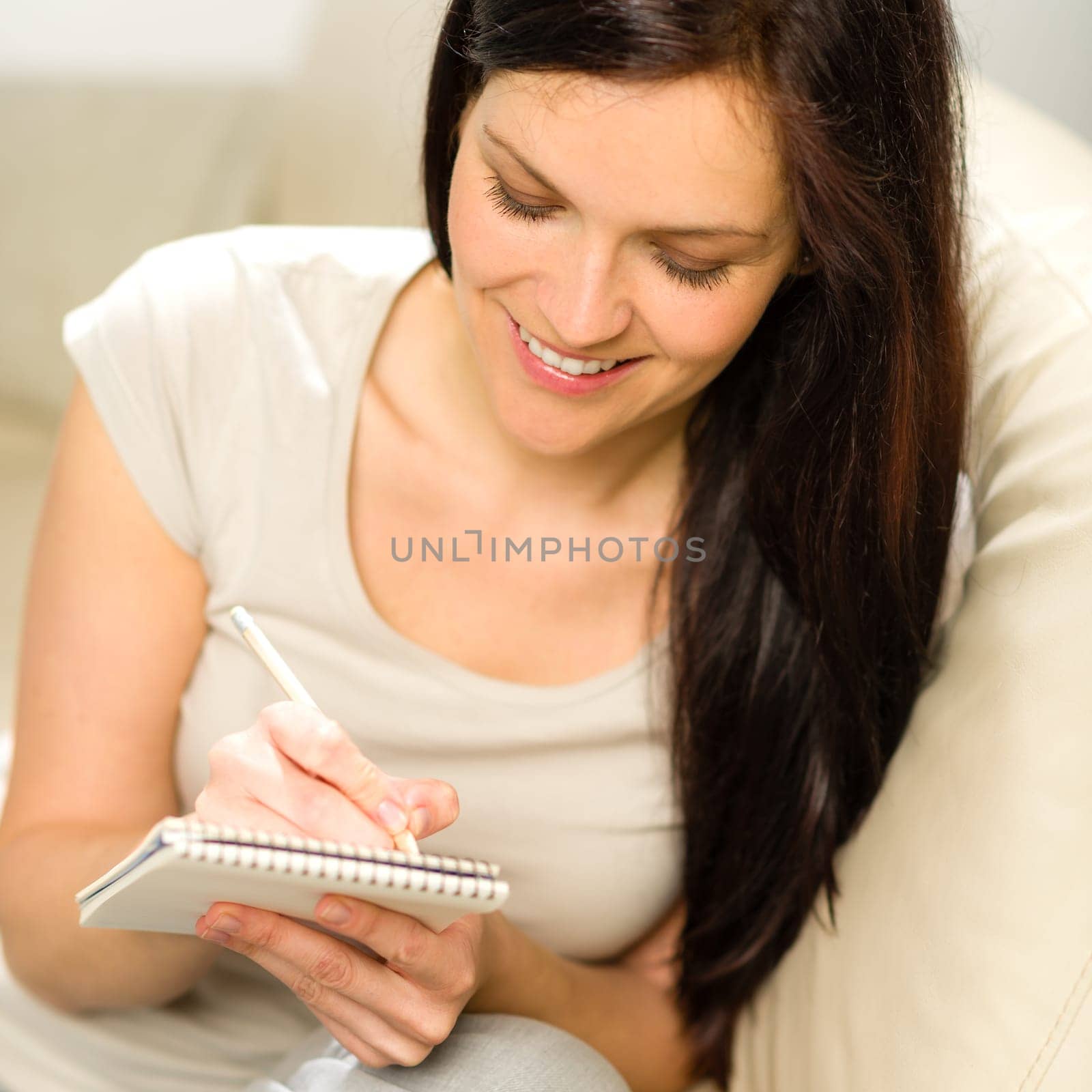 Pensive smiling woman writing her ideas to notebook