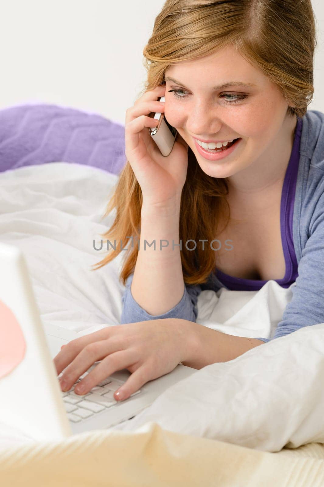Cheerful teenage girl using smart phone and laptop