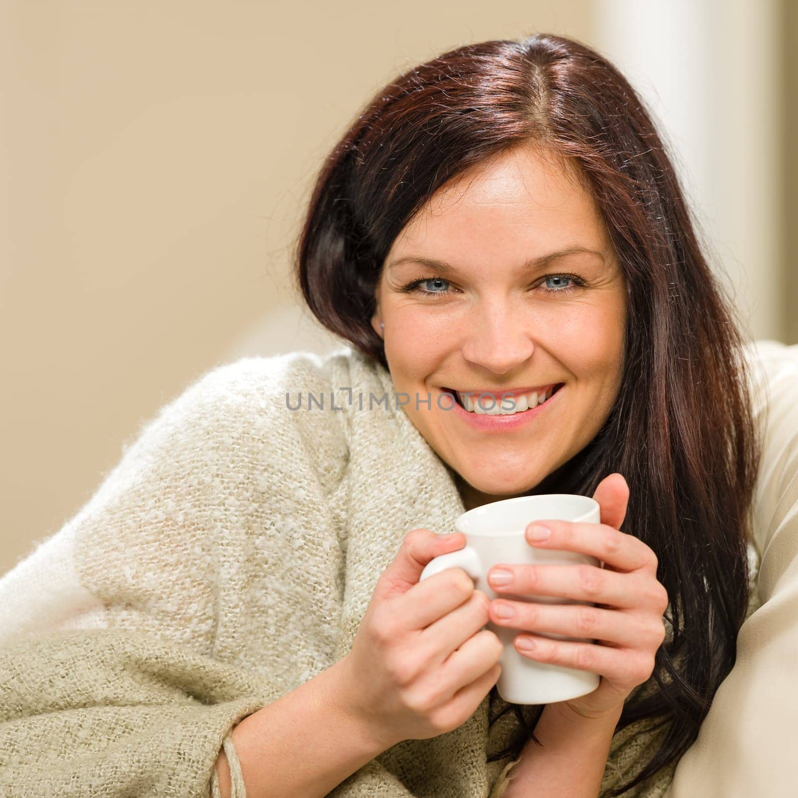 Portrait of joyful woman drinking hot beverage at home