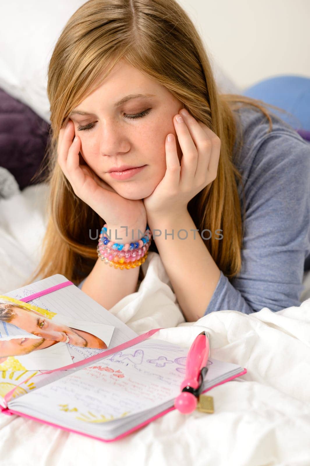 Sad teenage girl lying over her diary because unrequited love