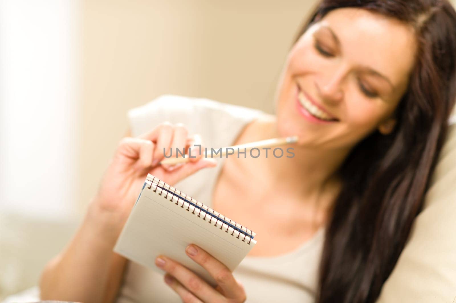 Pensive brunette woman writing to notebook