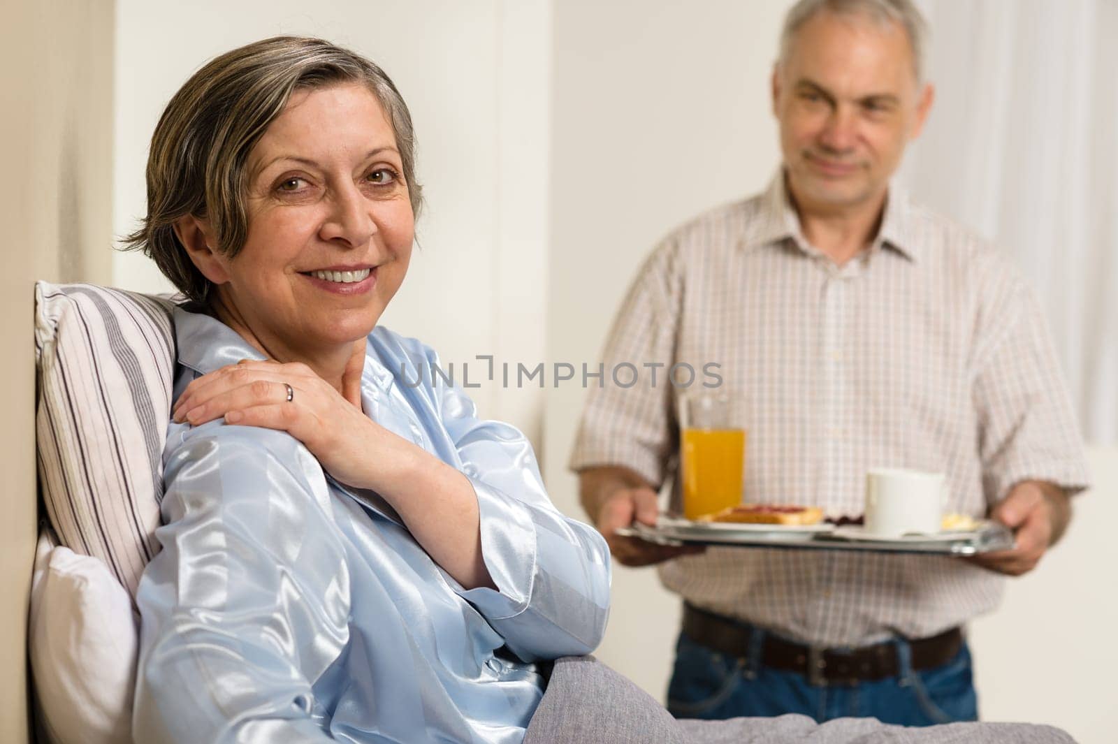 Caring senior man bringing breakfast to her sick wife