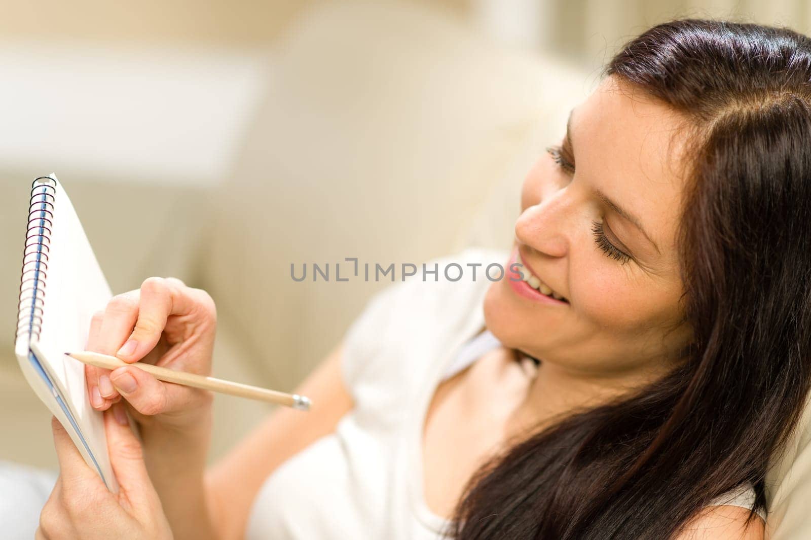 Happy woman taking notes into notepad using pencil