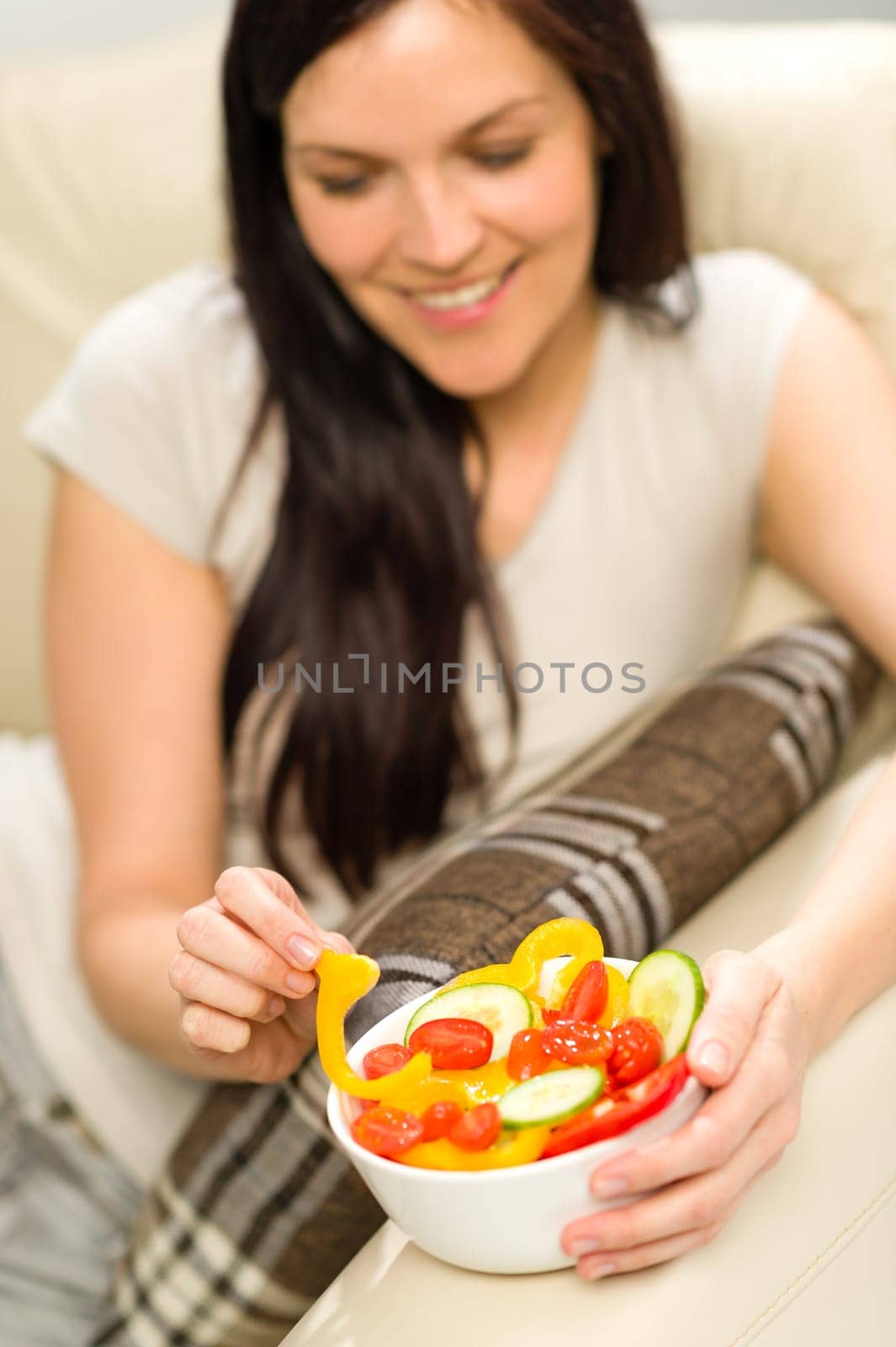 Joyful healthy woman eating bowl of fresh vegetables
