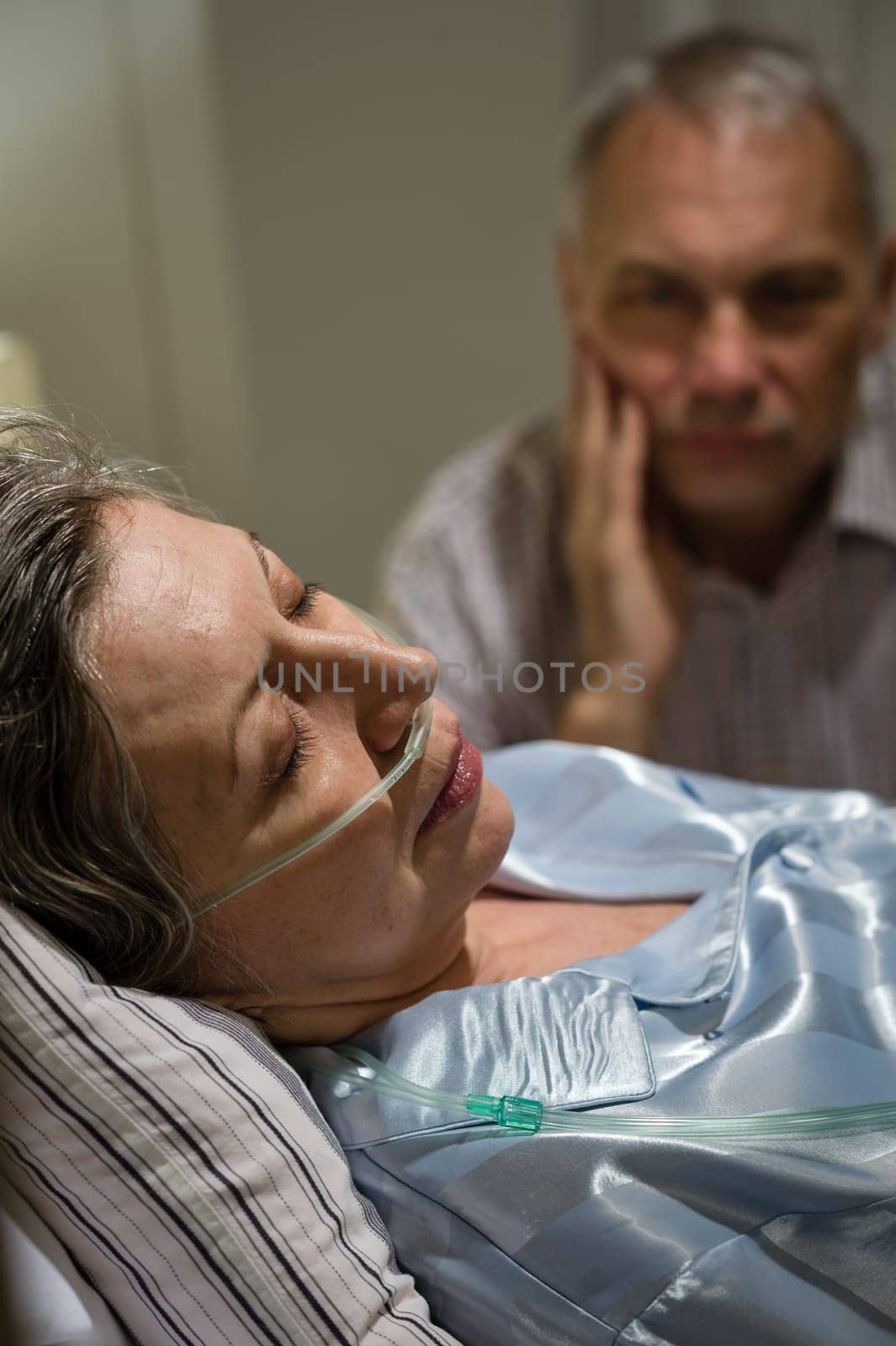 Dying old woman in hospital bed with caring man
