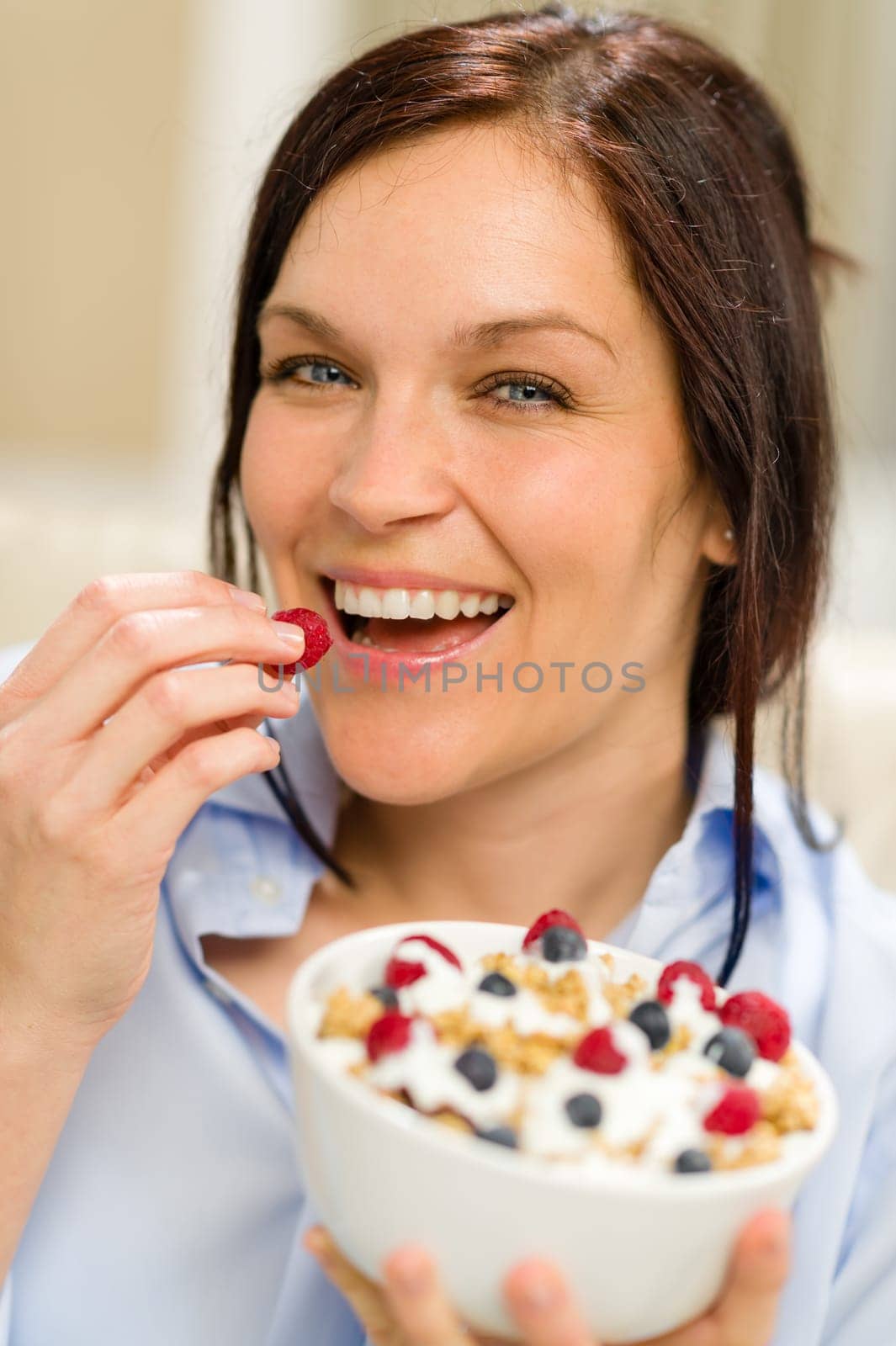 Joyful woman eating healthy cereal in the morning for breakfast