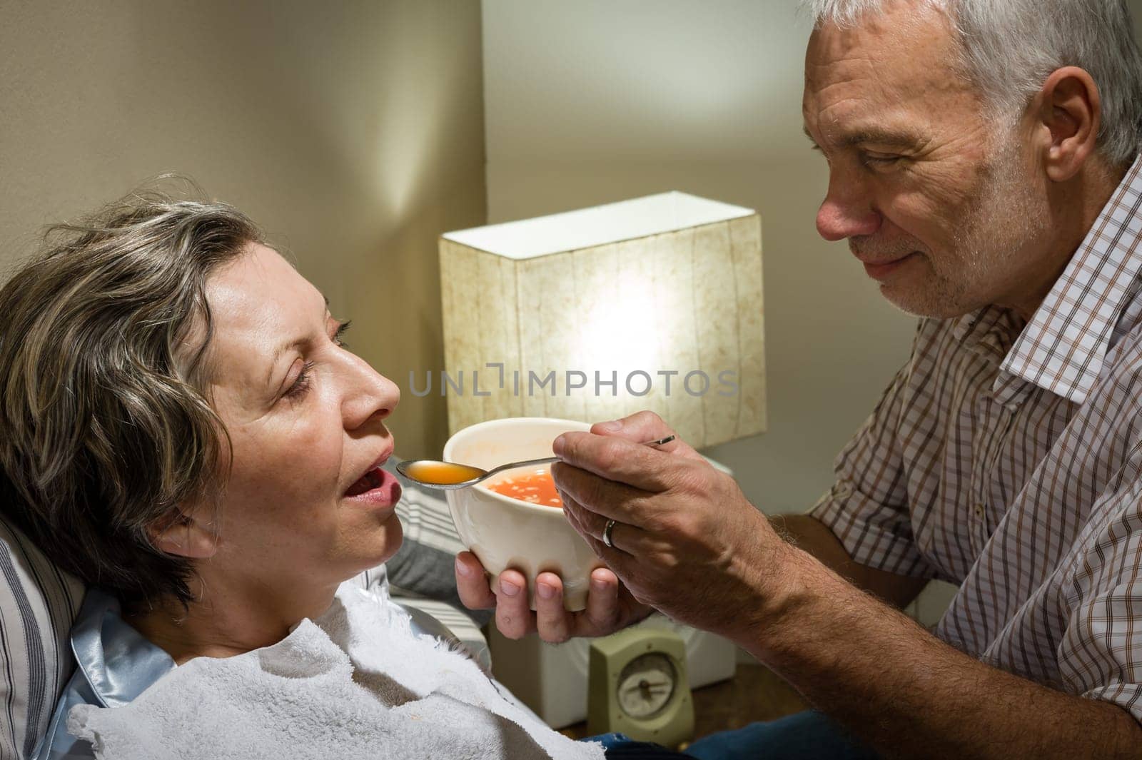 Loving retired husband feeding his ill wife with soup