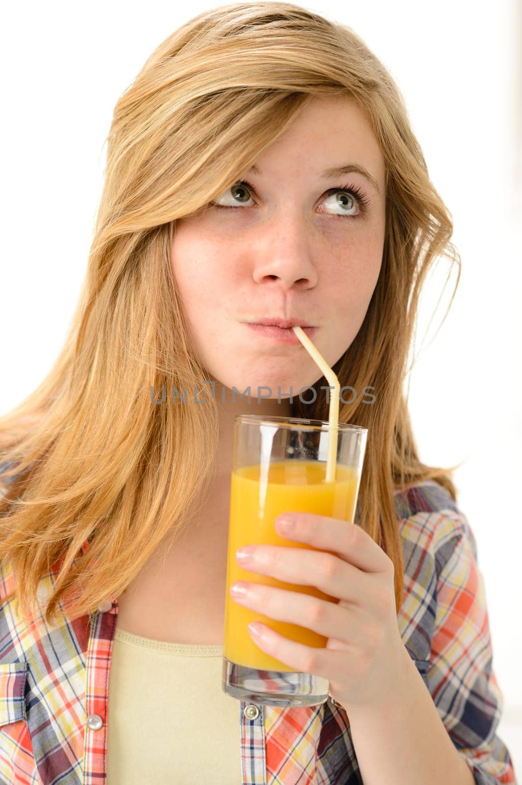 Dreamy blonde girl sipping orange juice in plaid shirt