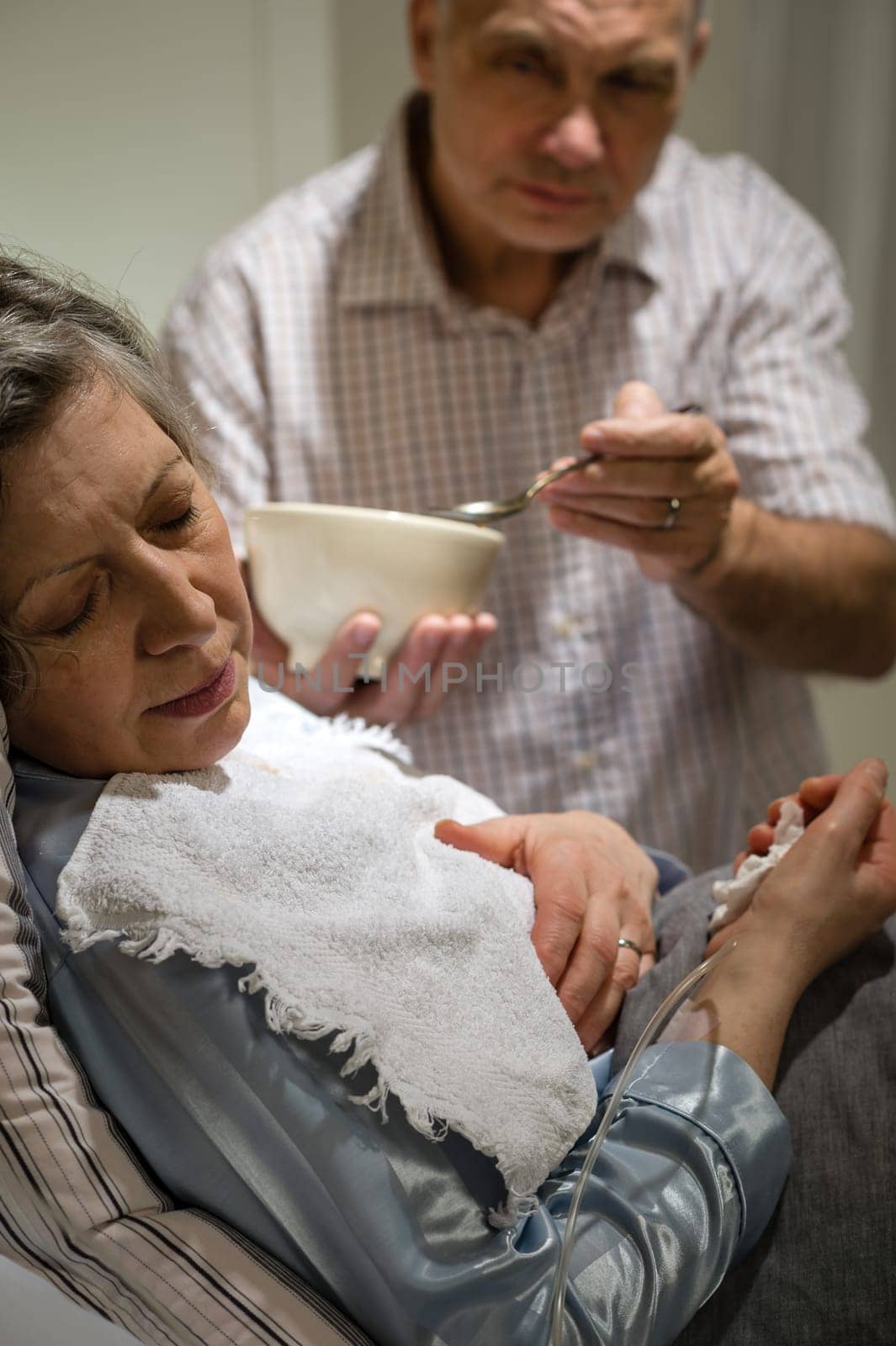 Mature man helping his ill wife feeding soup