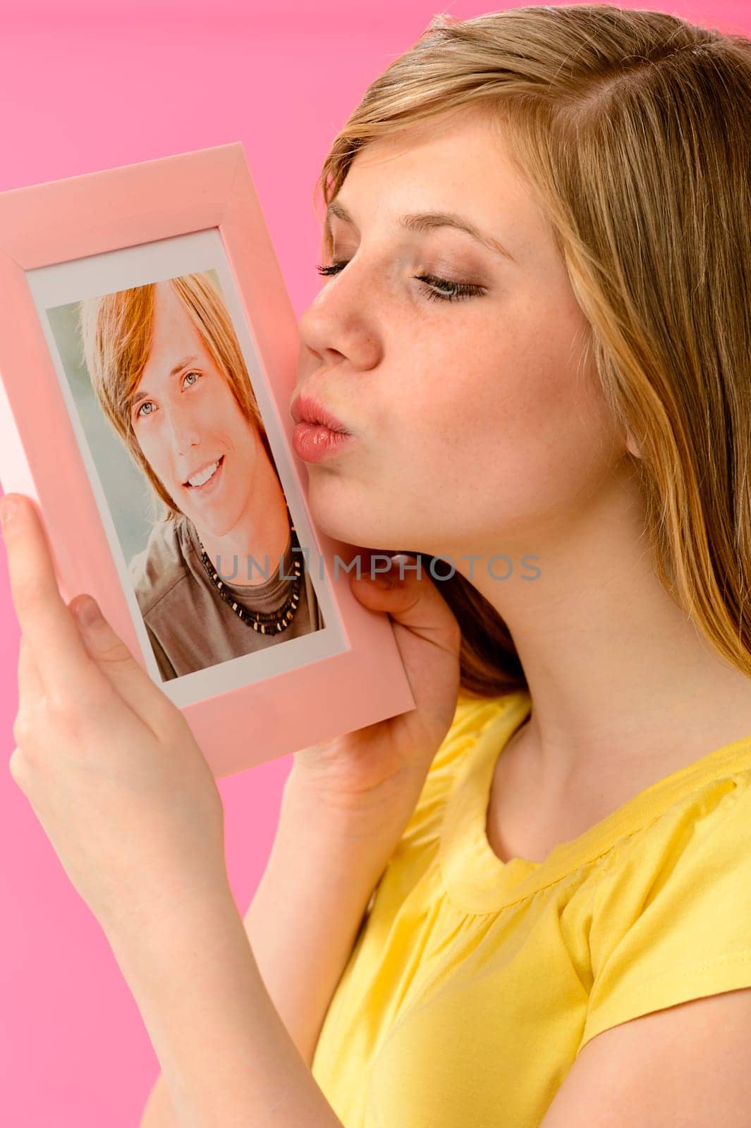 Young girl holding and kissing a picture of her love