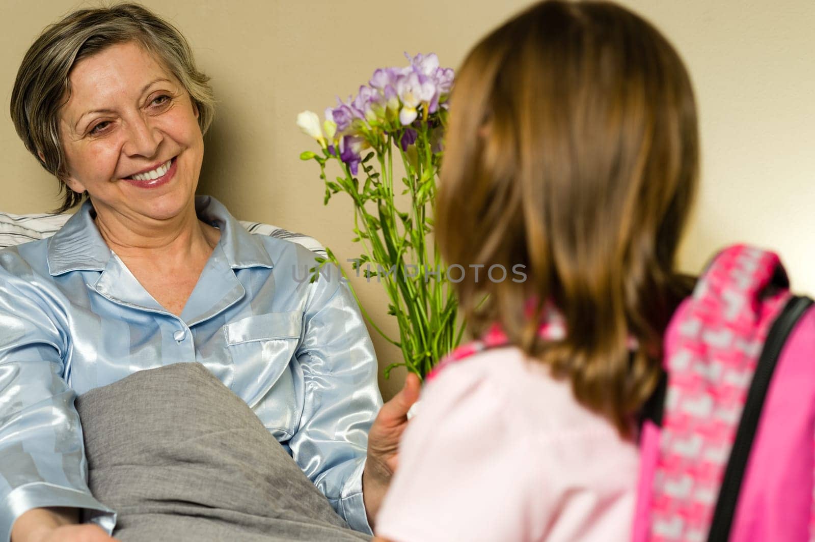 Little girl visiting her ill grandmother giving flowers