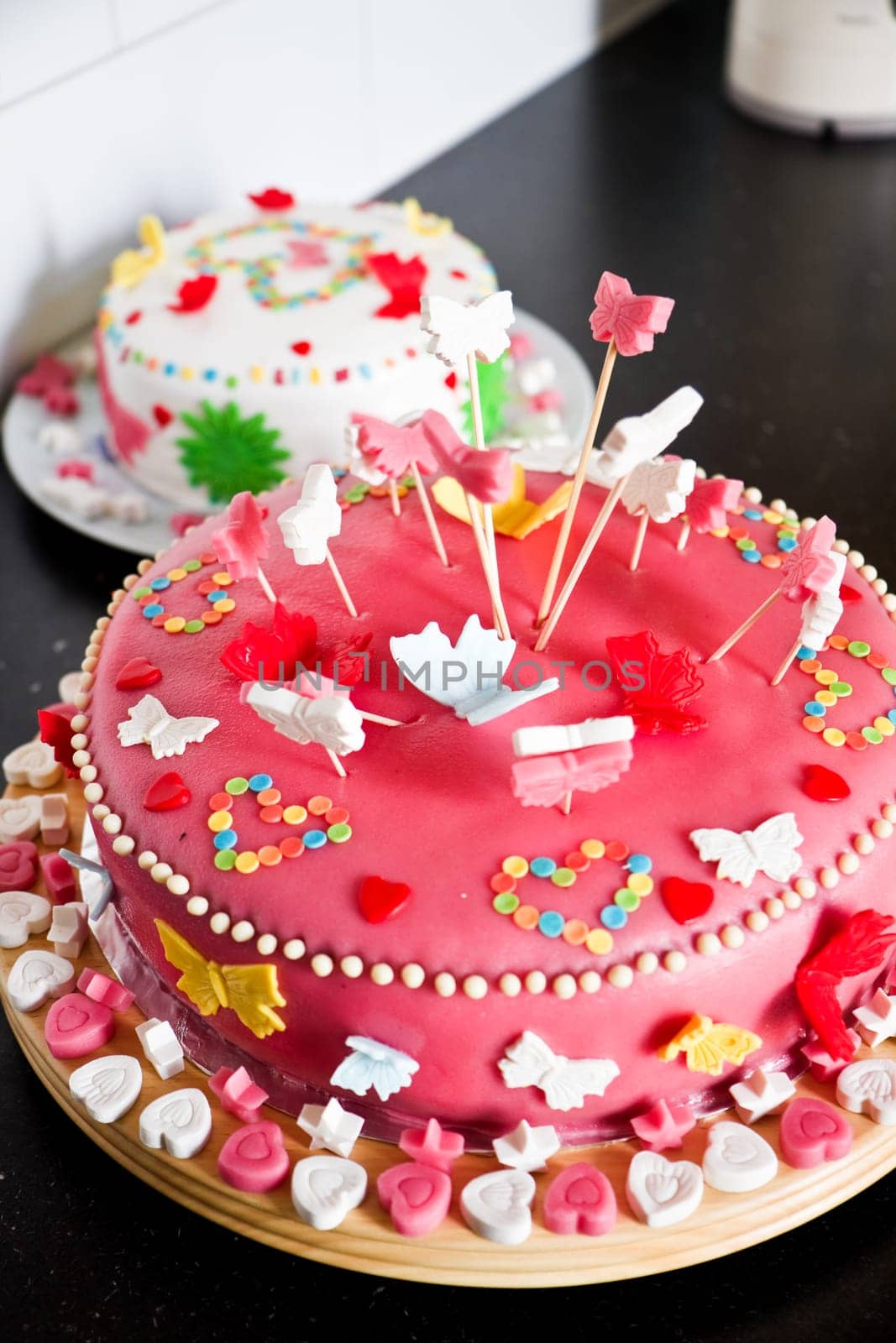 Delicious colorful decorated pink and white Marzipan cakes for a birthday party on kitchen dresser