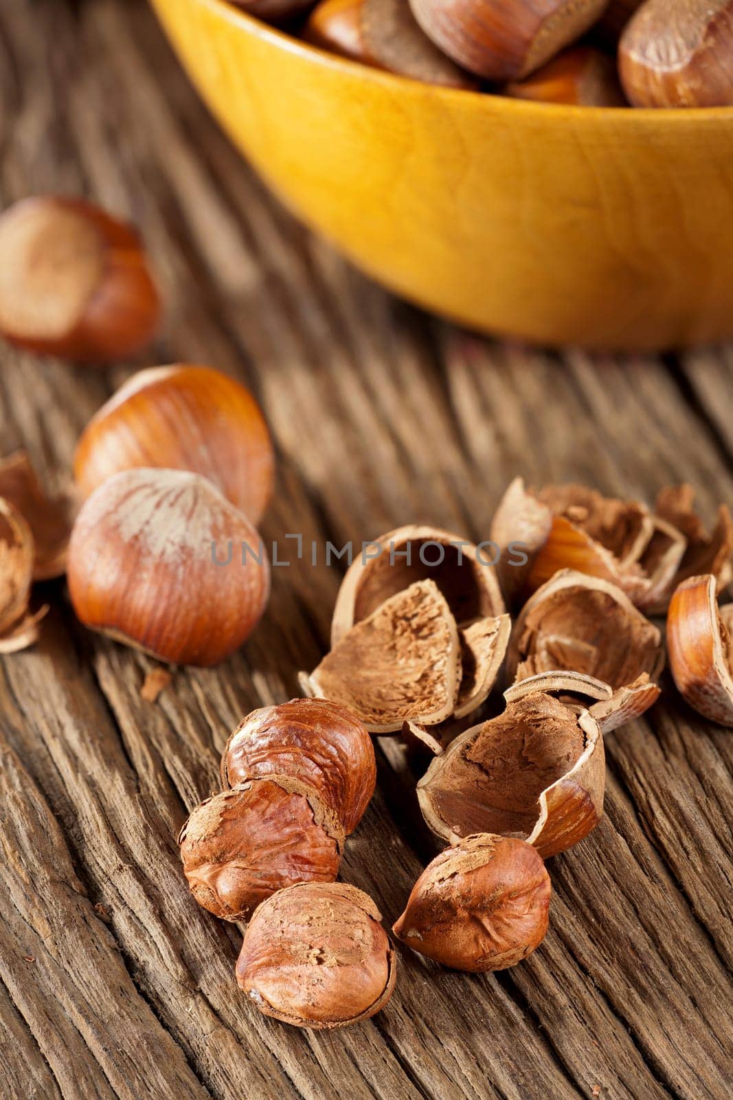 Hazelnut kernels and shells and a shell with hazelnuts in the background on a rustic wooden surface