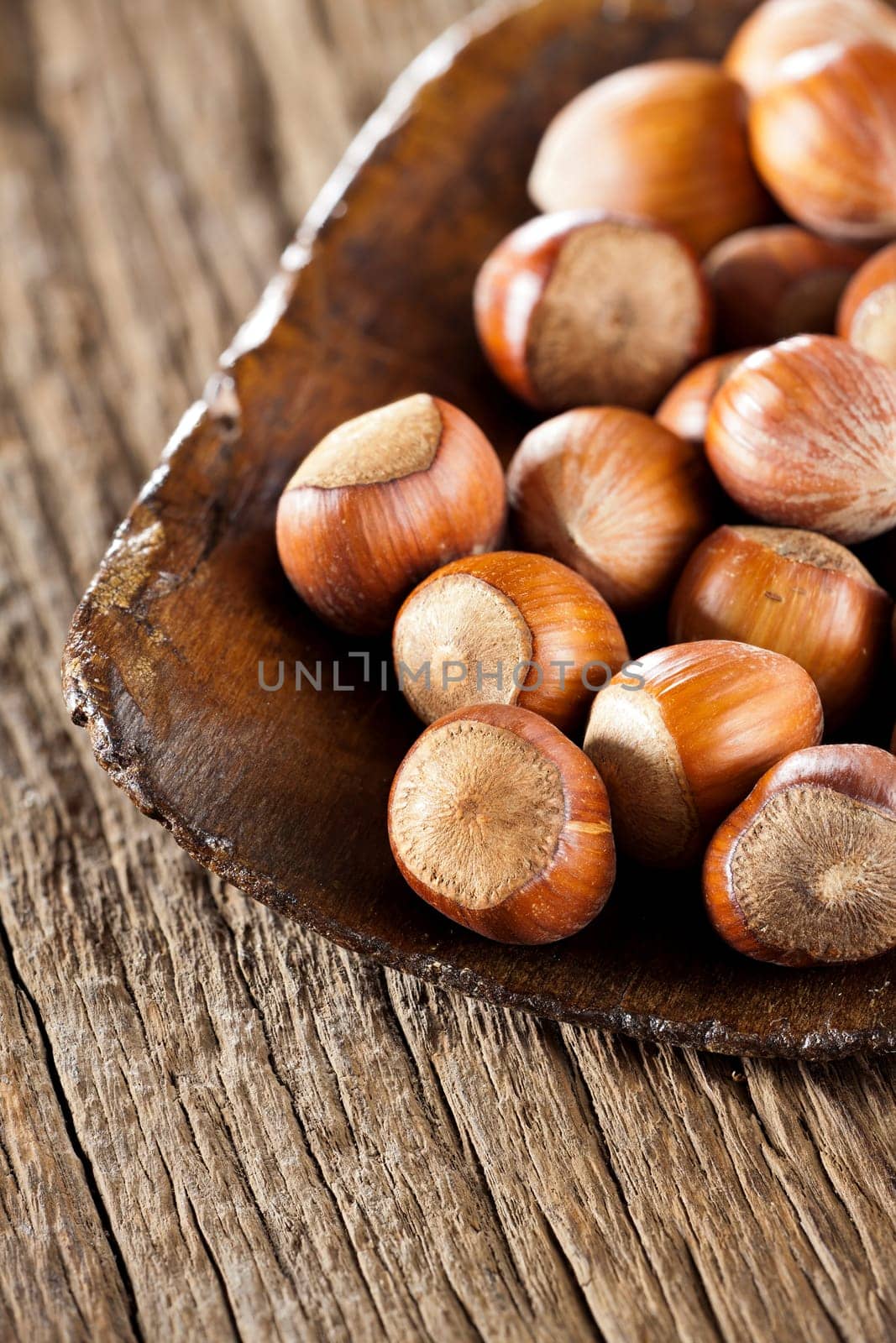 Whole hazelnuts in a very old wooden shovel on rustic wood background