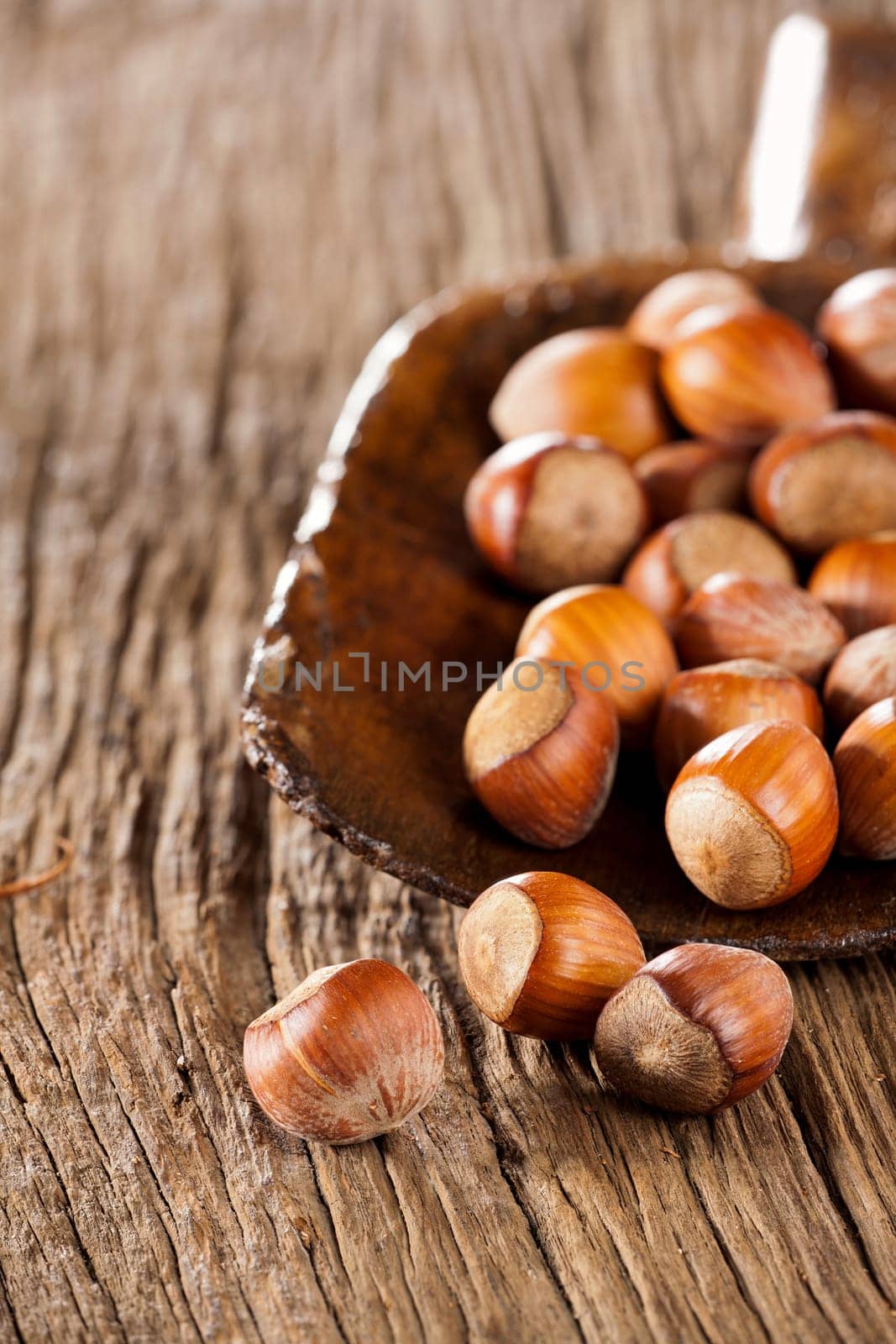 Whole hazelnuts in a very old wooden shovel on rustic wood background
