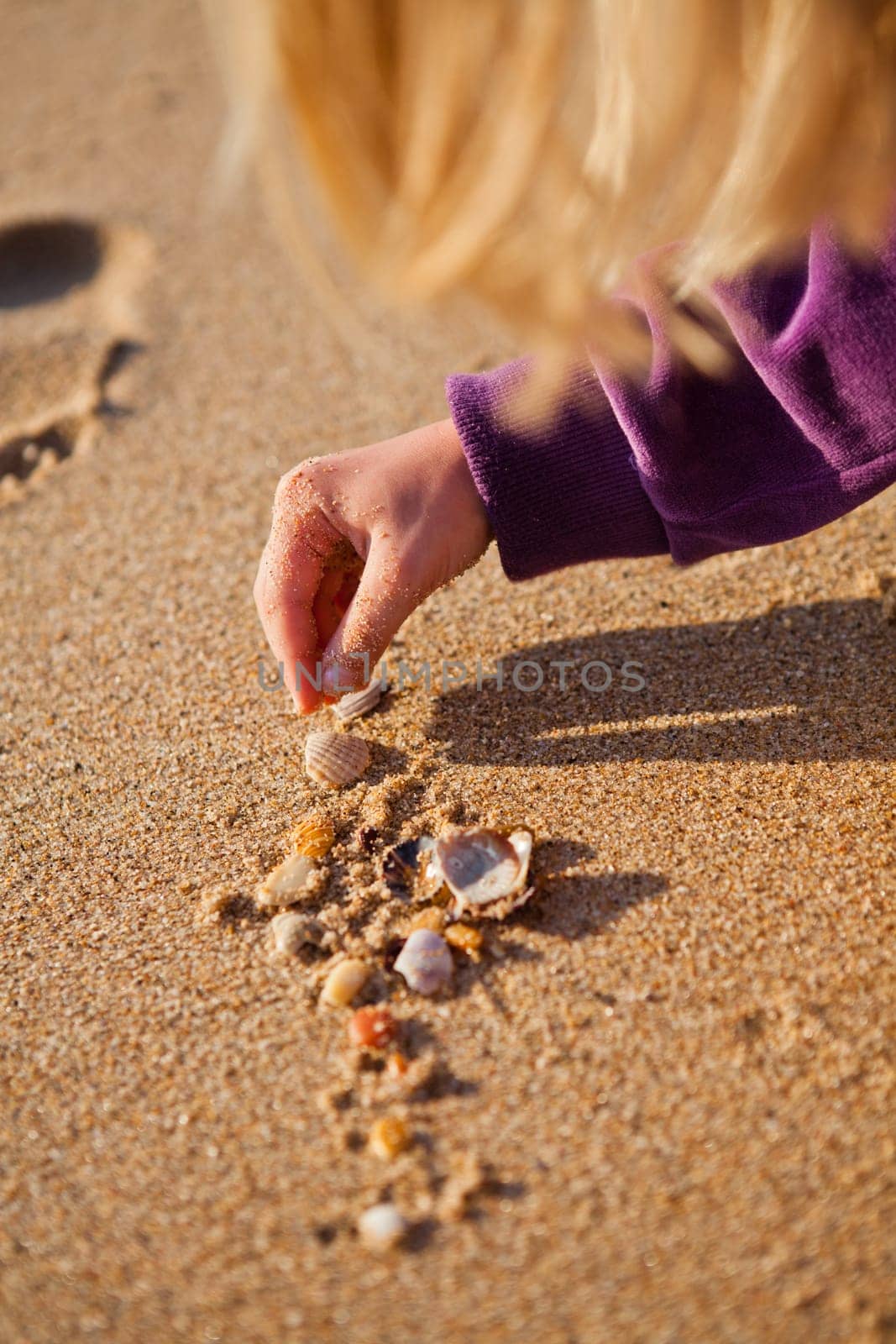 Closeup of young girl playing with shells on beach