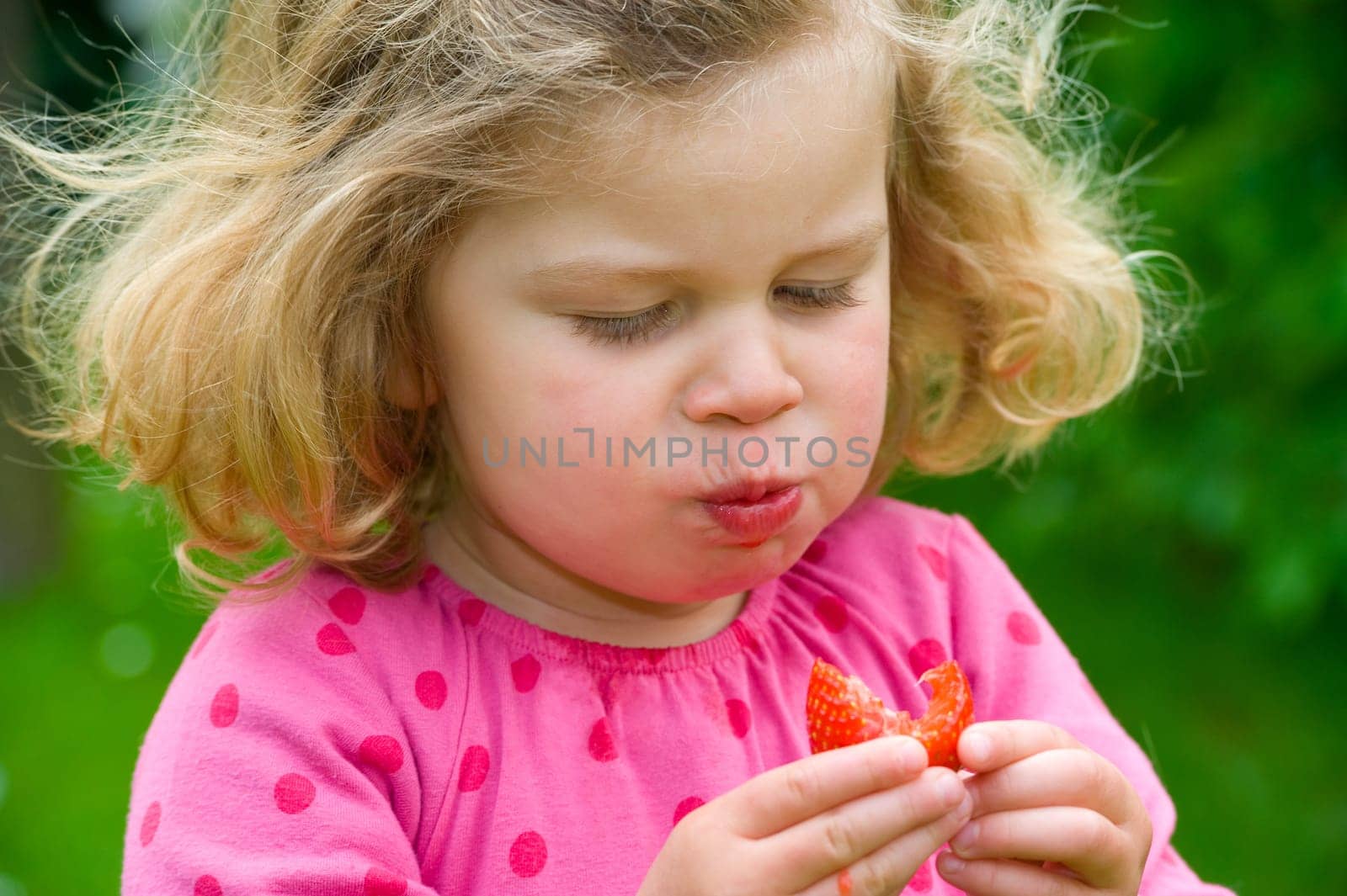 Little girl is eating strawberry