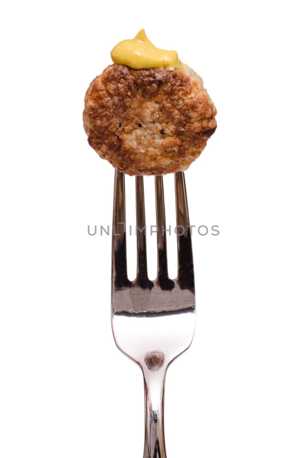 Fried meatball with yellow mustard on a fork in portrait format