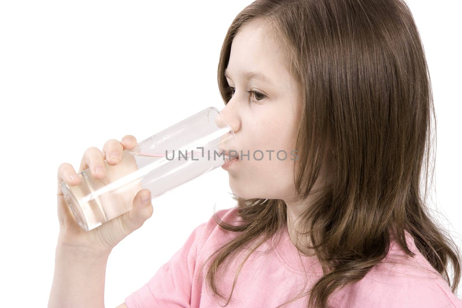 The girl drinks water from a transparent glass
