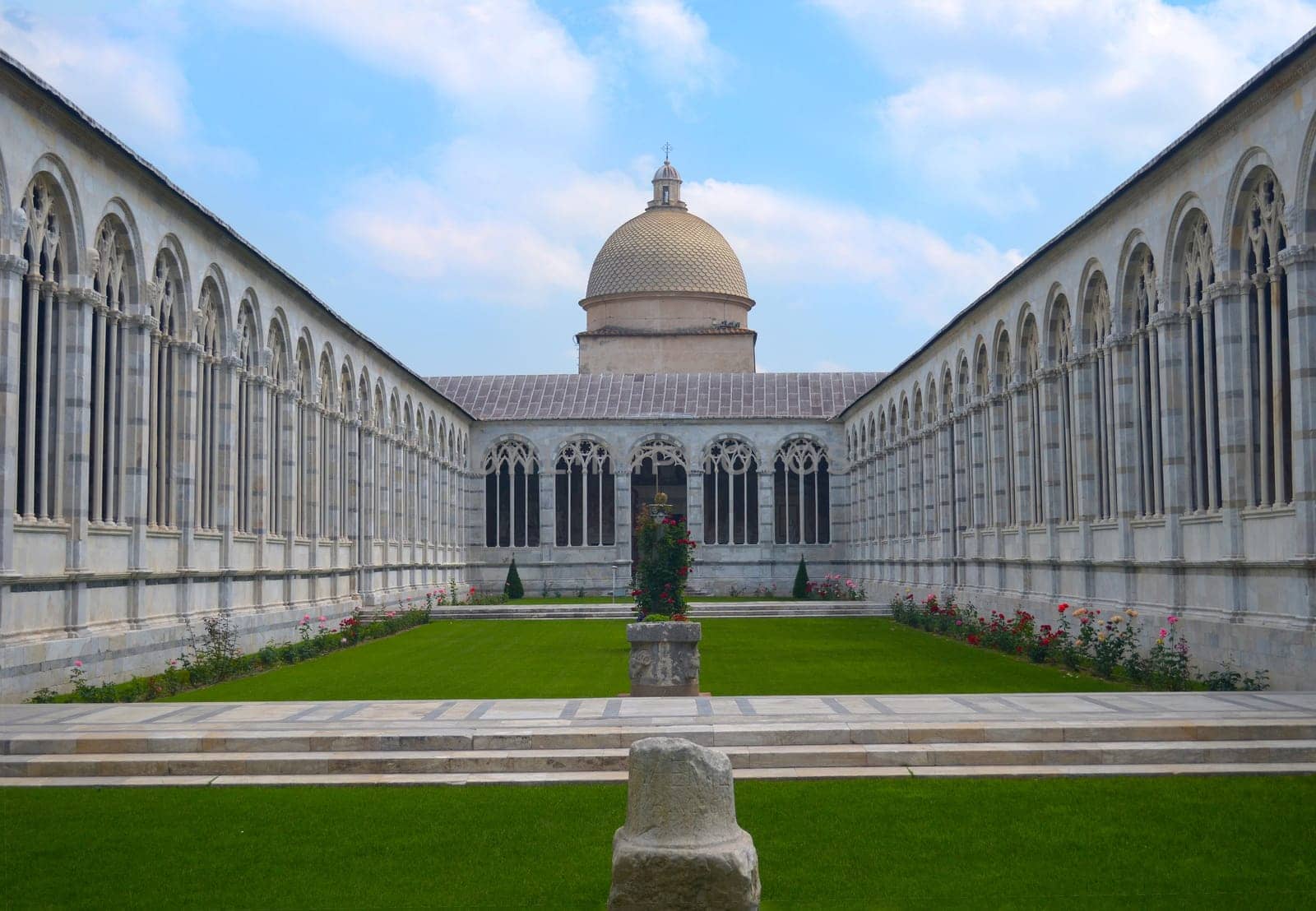 Historical courtyard garden with arched building around it and green lawn