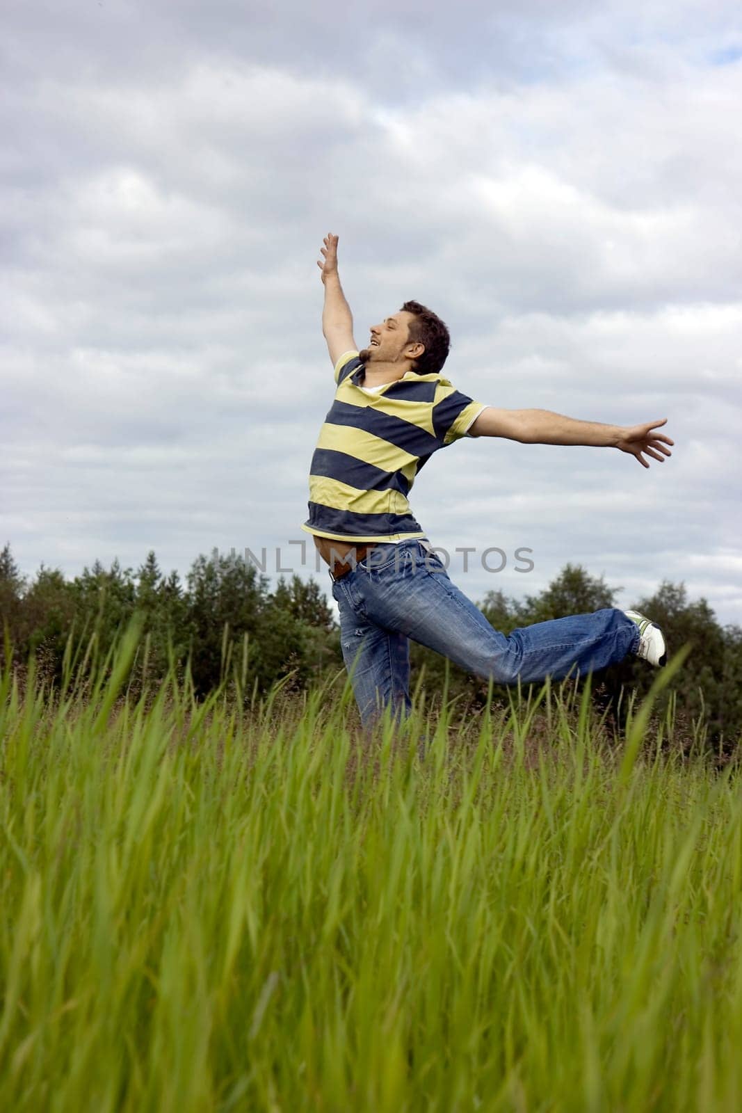 The young man joyfully jumps on a grass
