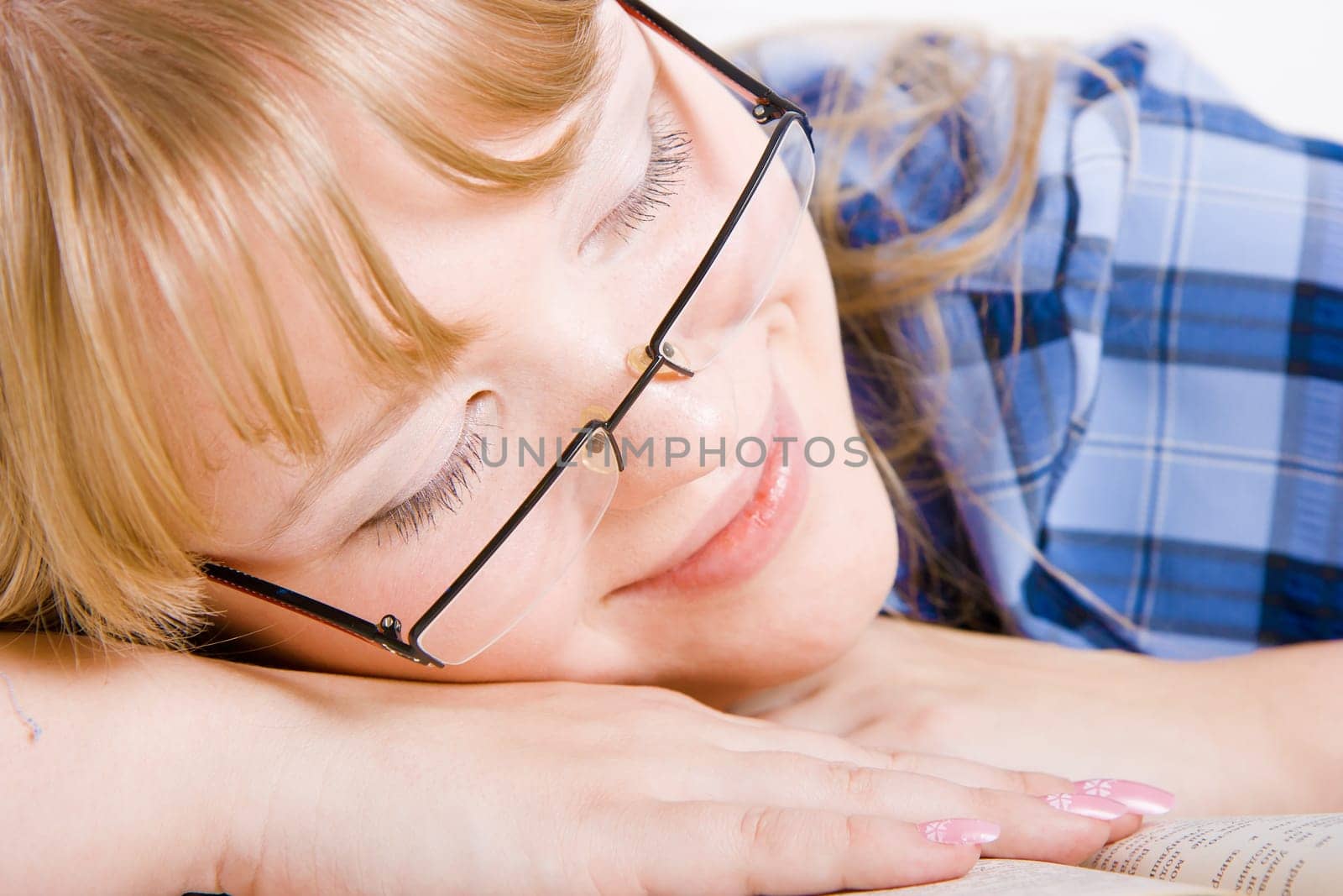 smiling blonde in glasses asleep on a book