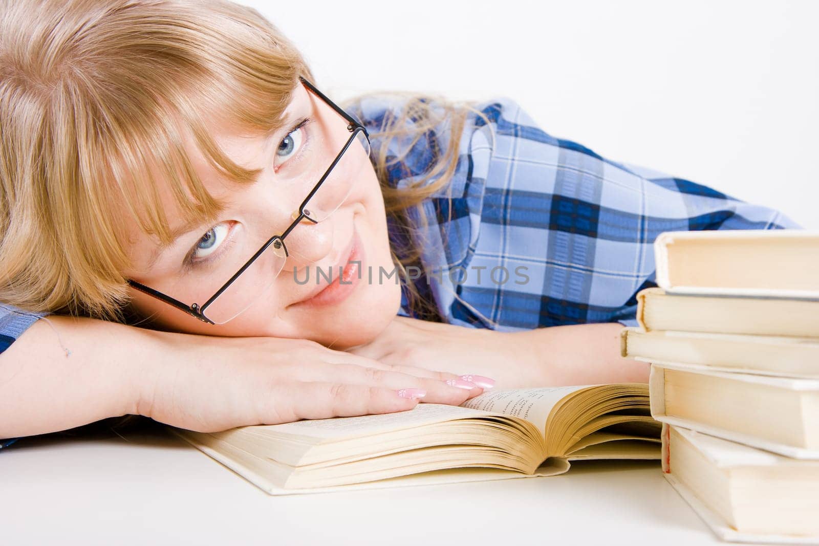 smiling blonde in glasses resting on a table with books