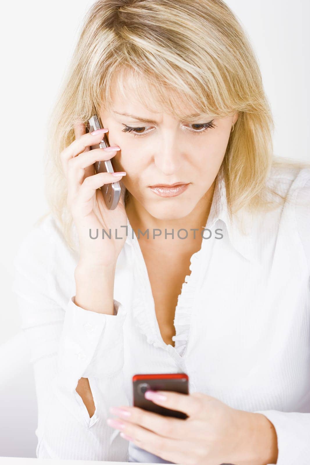 surprised blonde with two mobile phones on a white background
