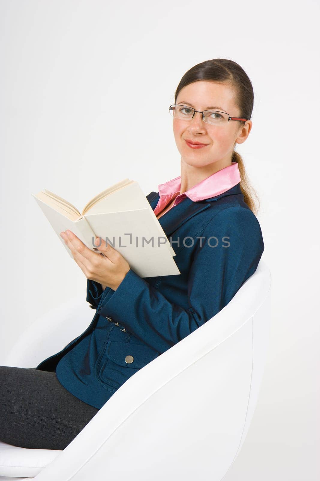girl with a book on a white background sits in a chair