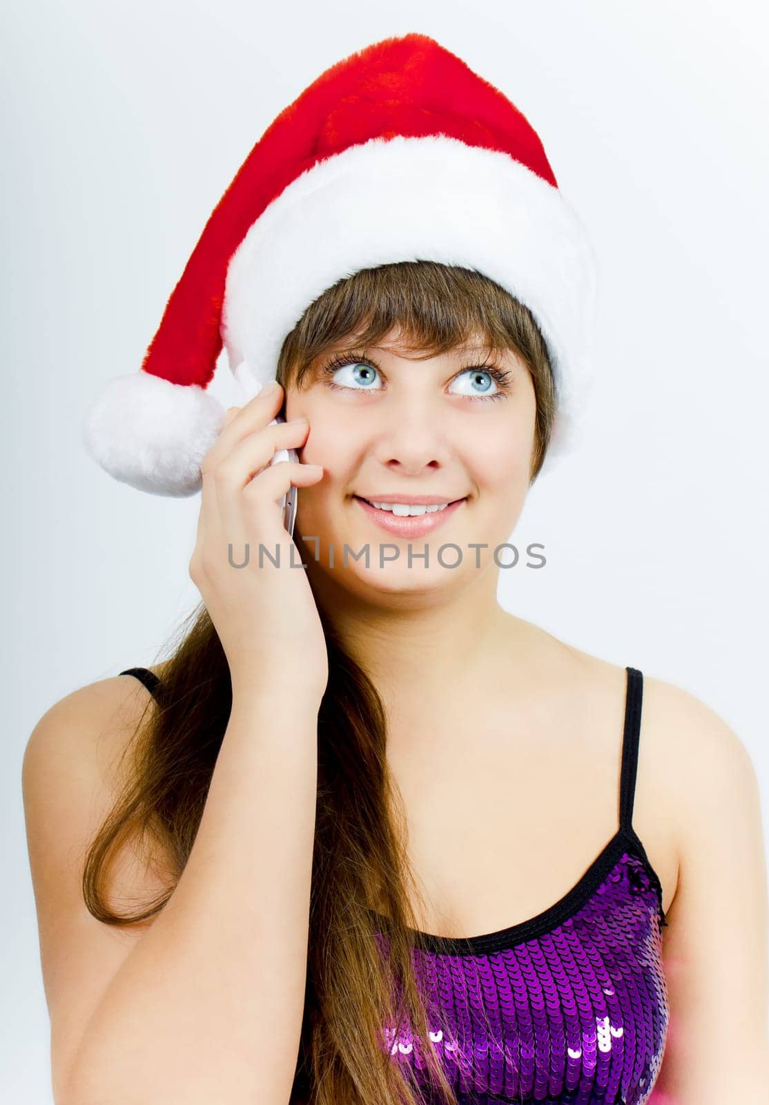 happy smiling girl with Santa hat with a phone on a light background. Studio photography