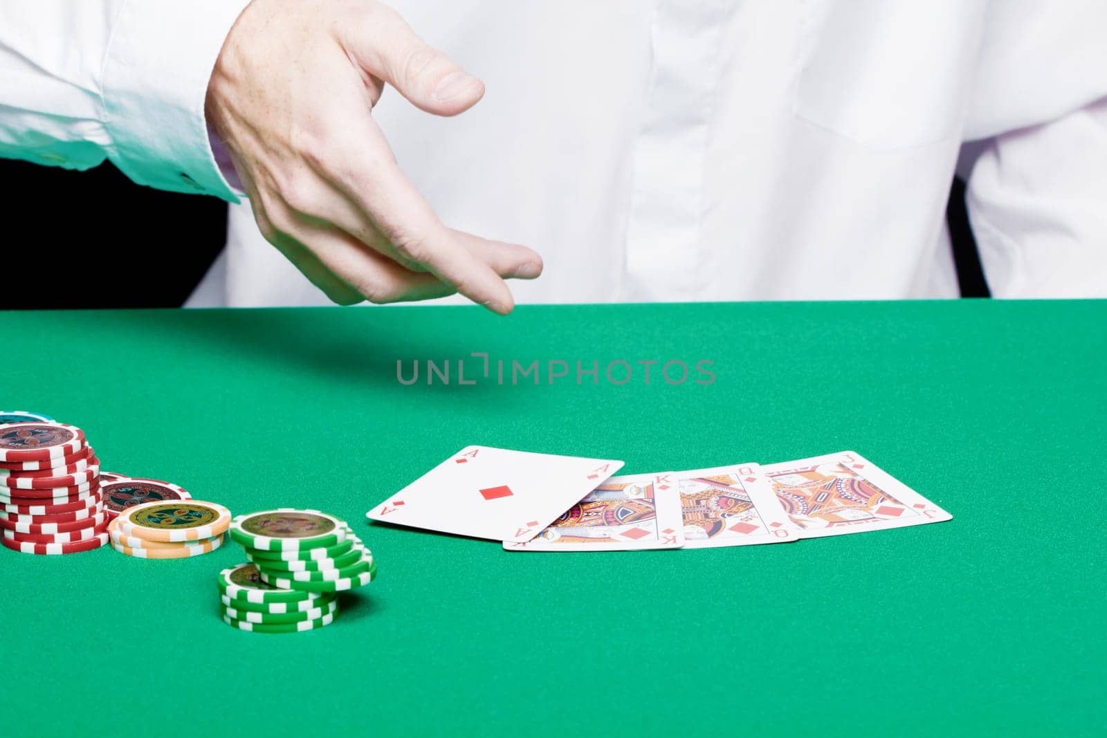 player's hand with cards and poker chips on a green table