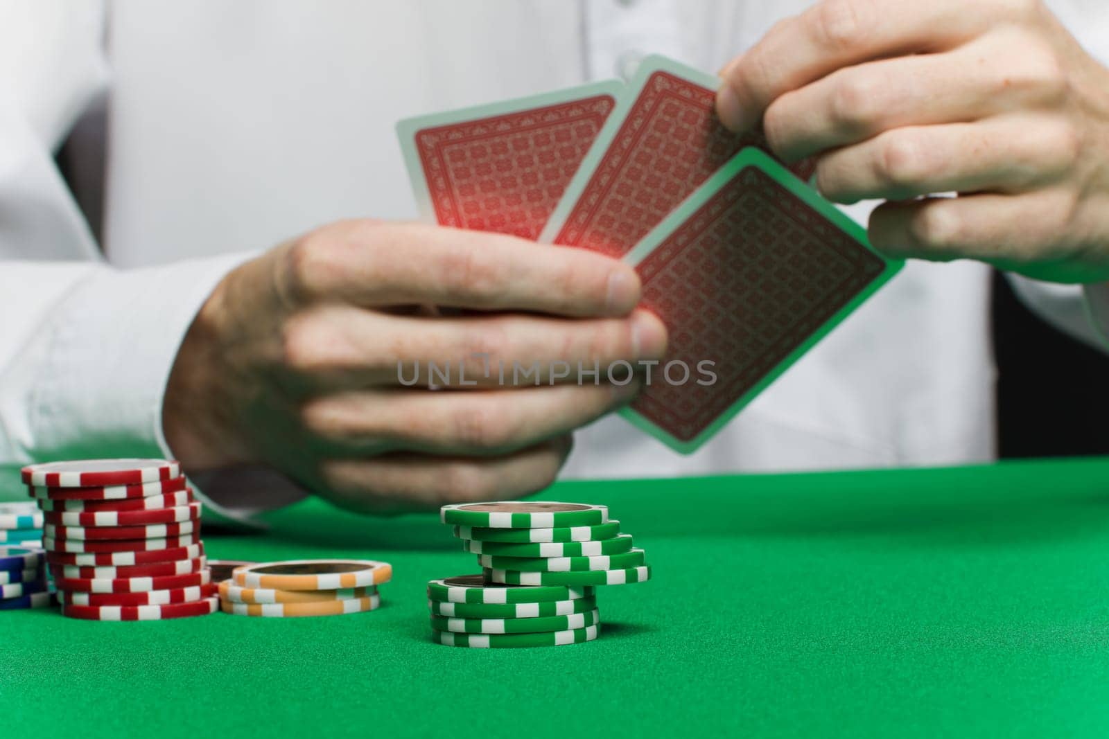 poker chips and the player's hand with the cards on the green game table