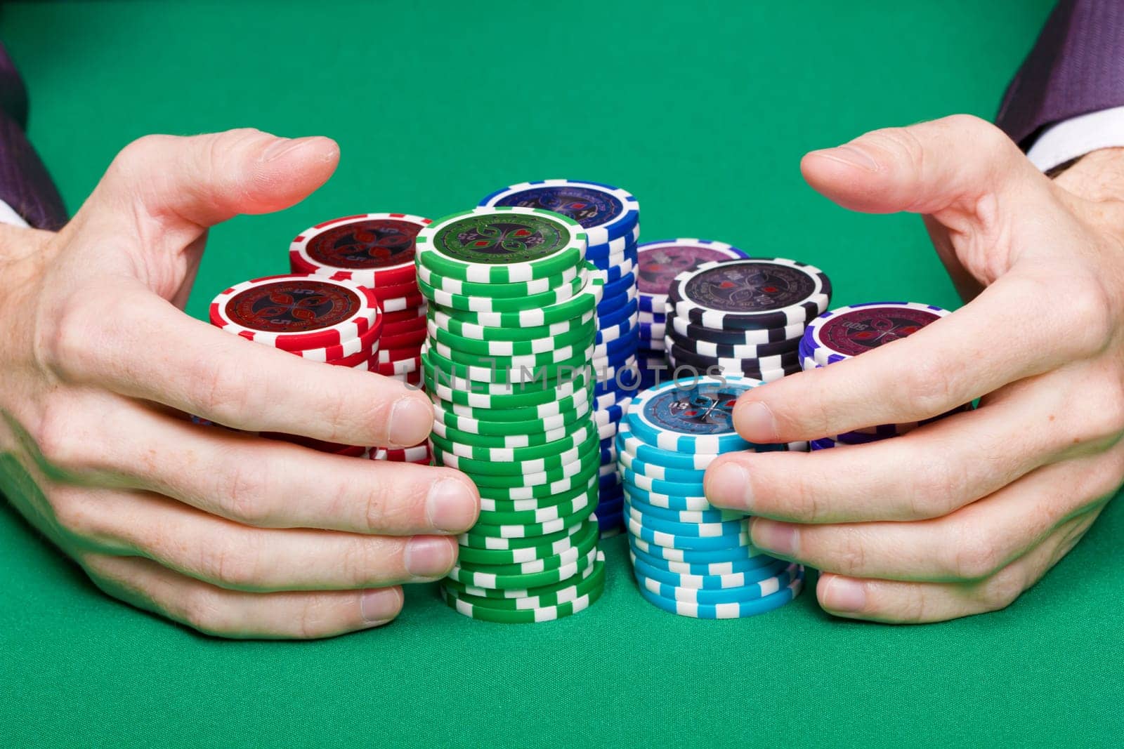 man with two hands rakes the pile of poker chips