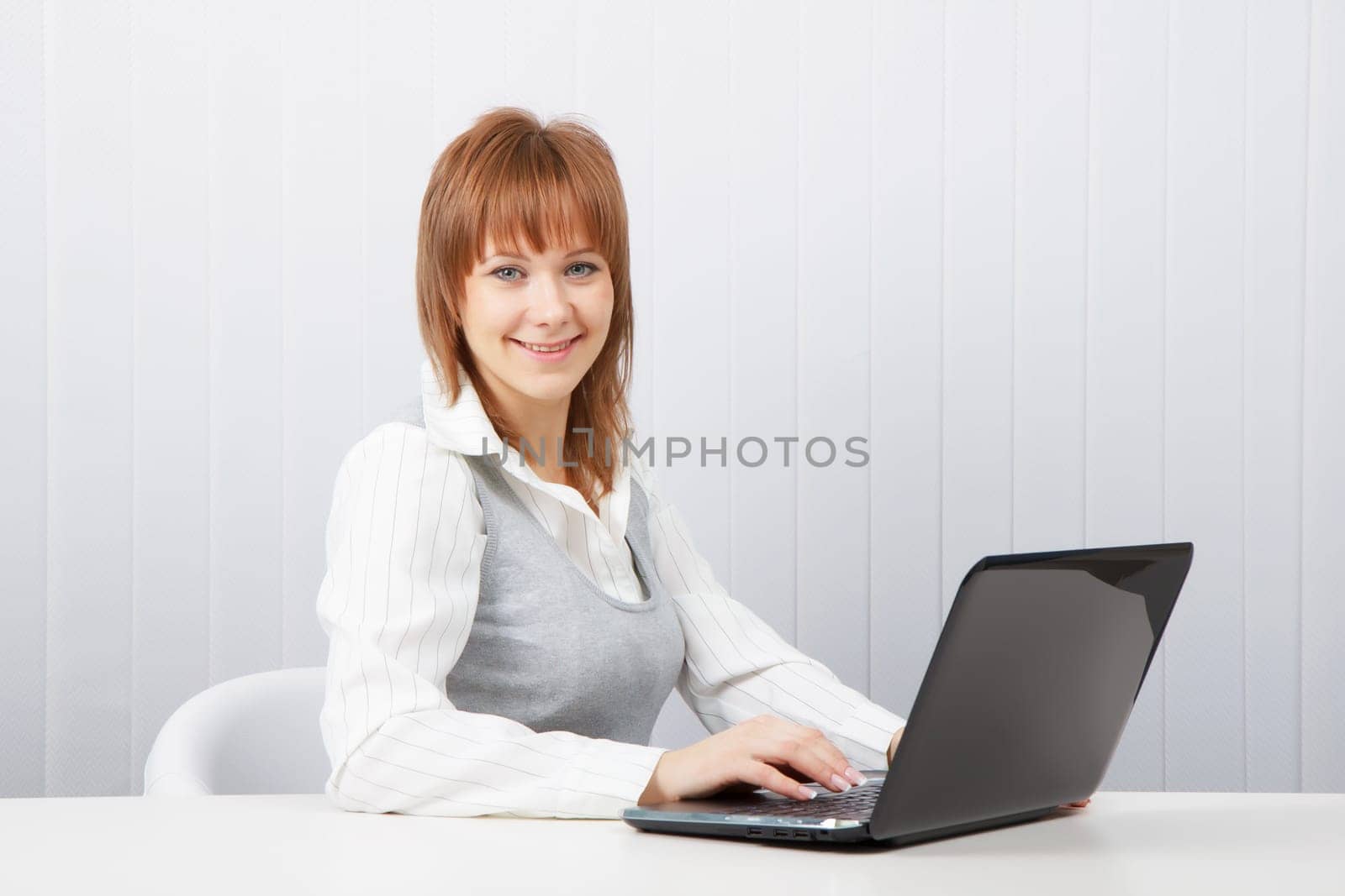 Attractive smiling happy girl with a laptop in the office