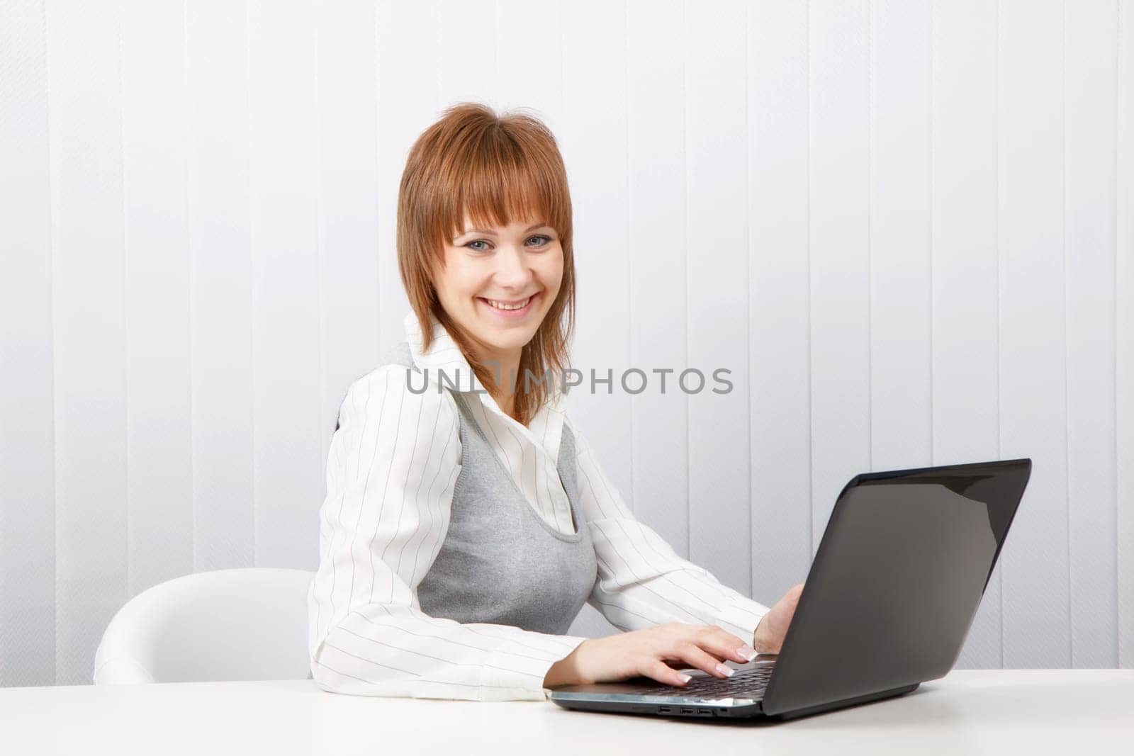 Attractive smiling happy girl with a laptop in the office