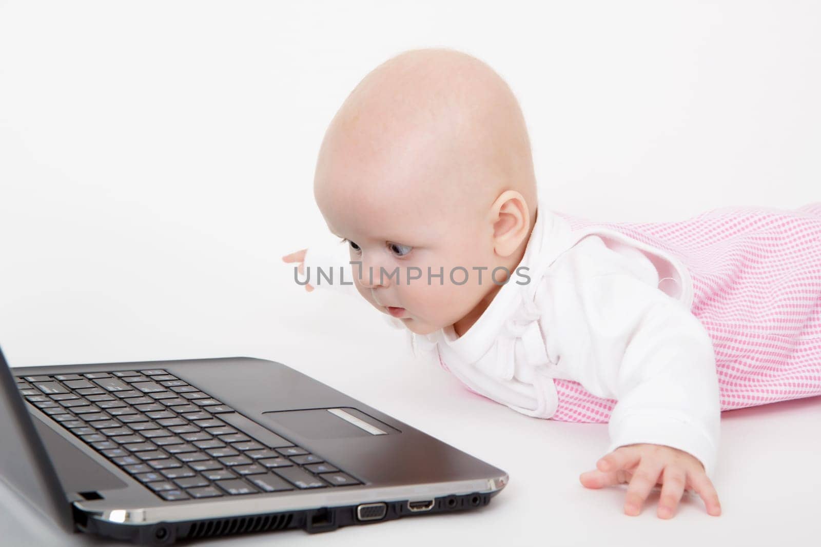 baby with laptop lying on a light background