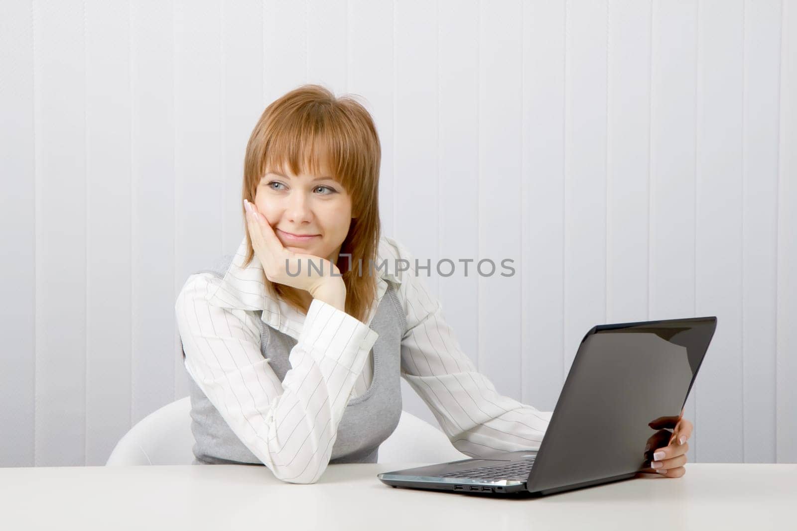 Attractive relaxed and smiling girl with a laptop in the office