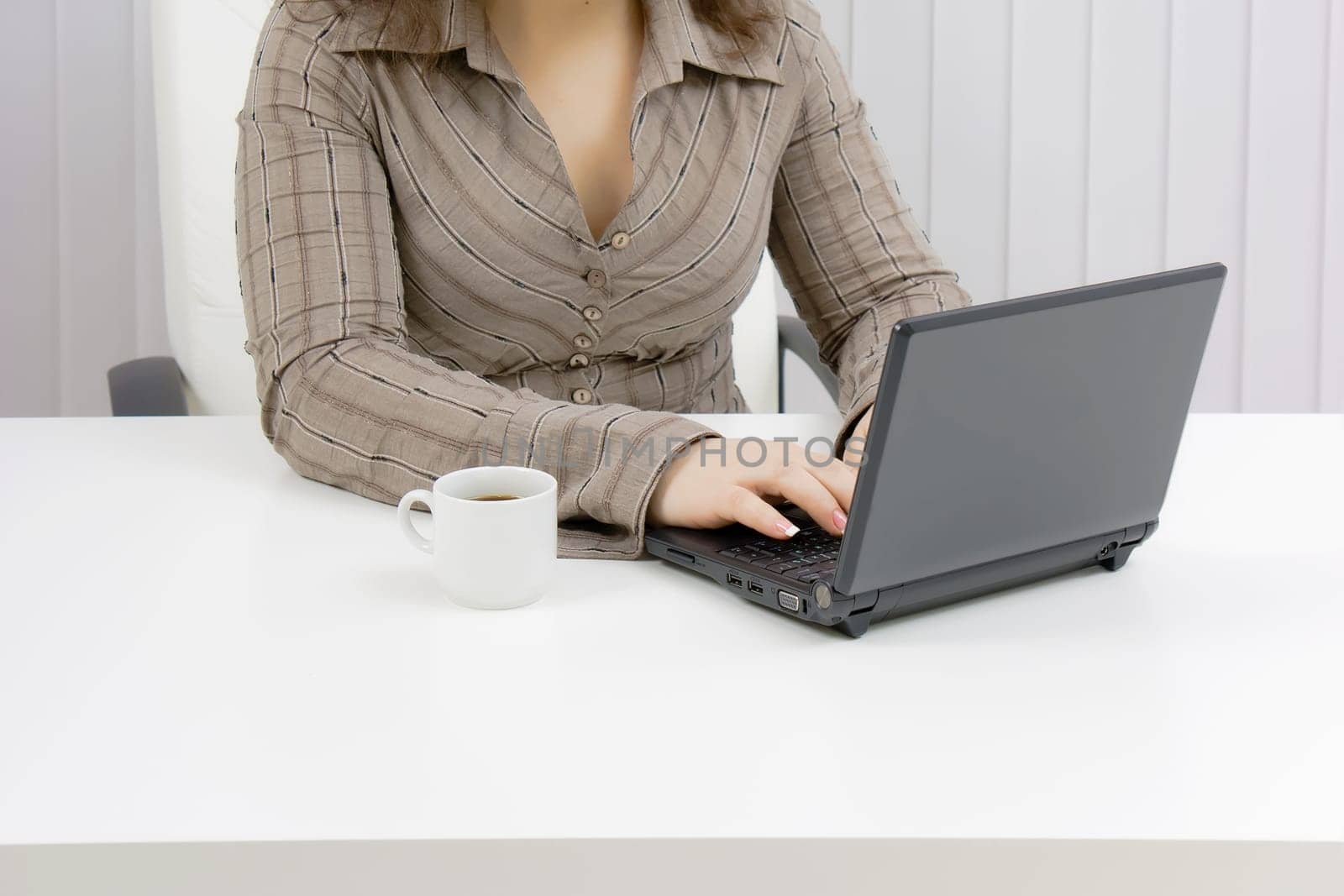 girl with a laptop works in an office. Part of the body