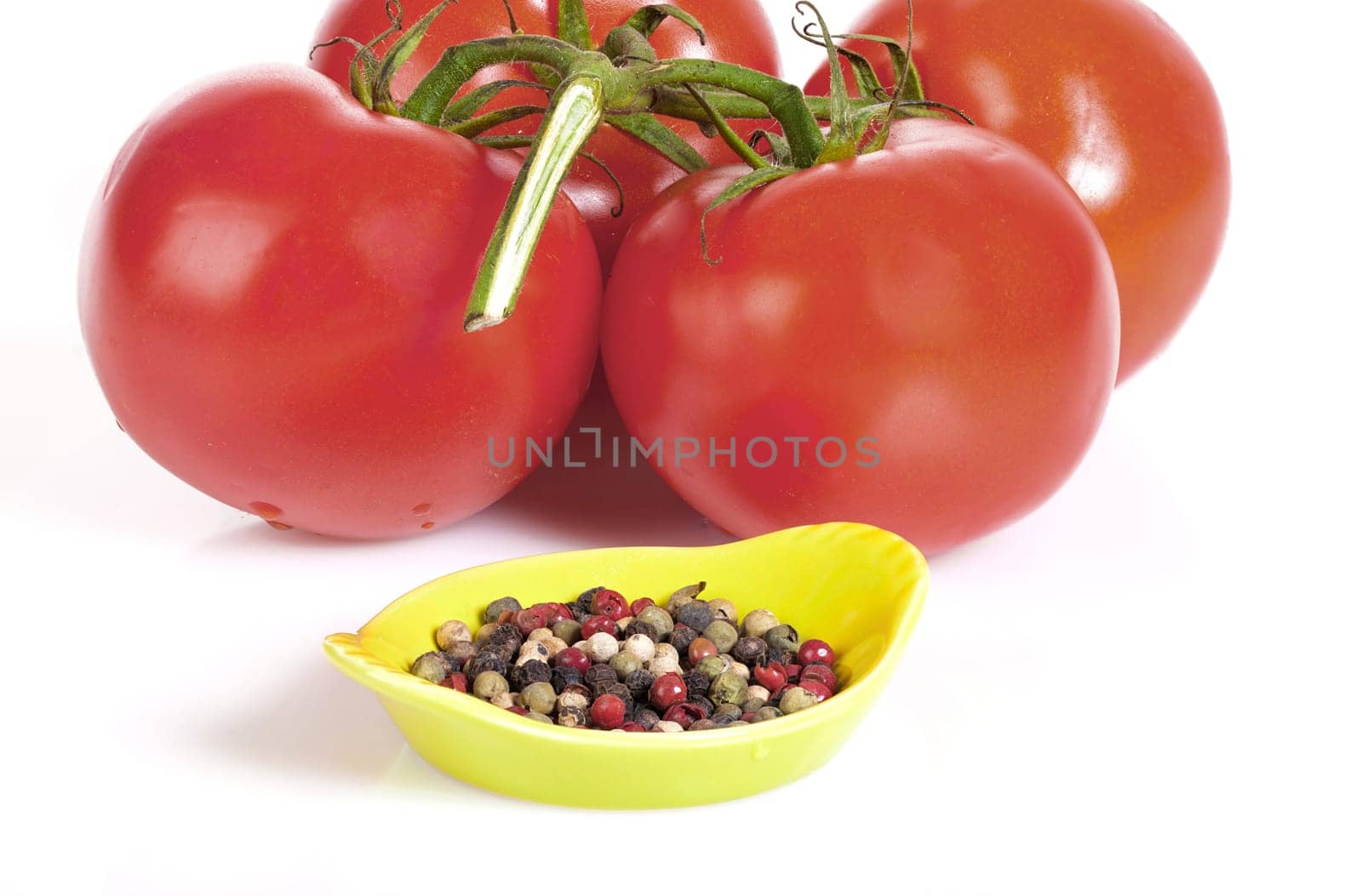 Fresh vine tomatoes with a bowl of peppercorns insulated on a white background
