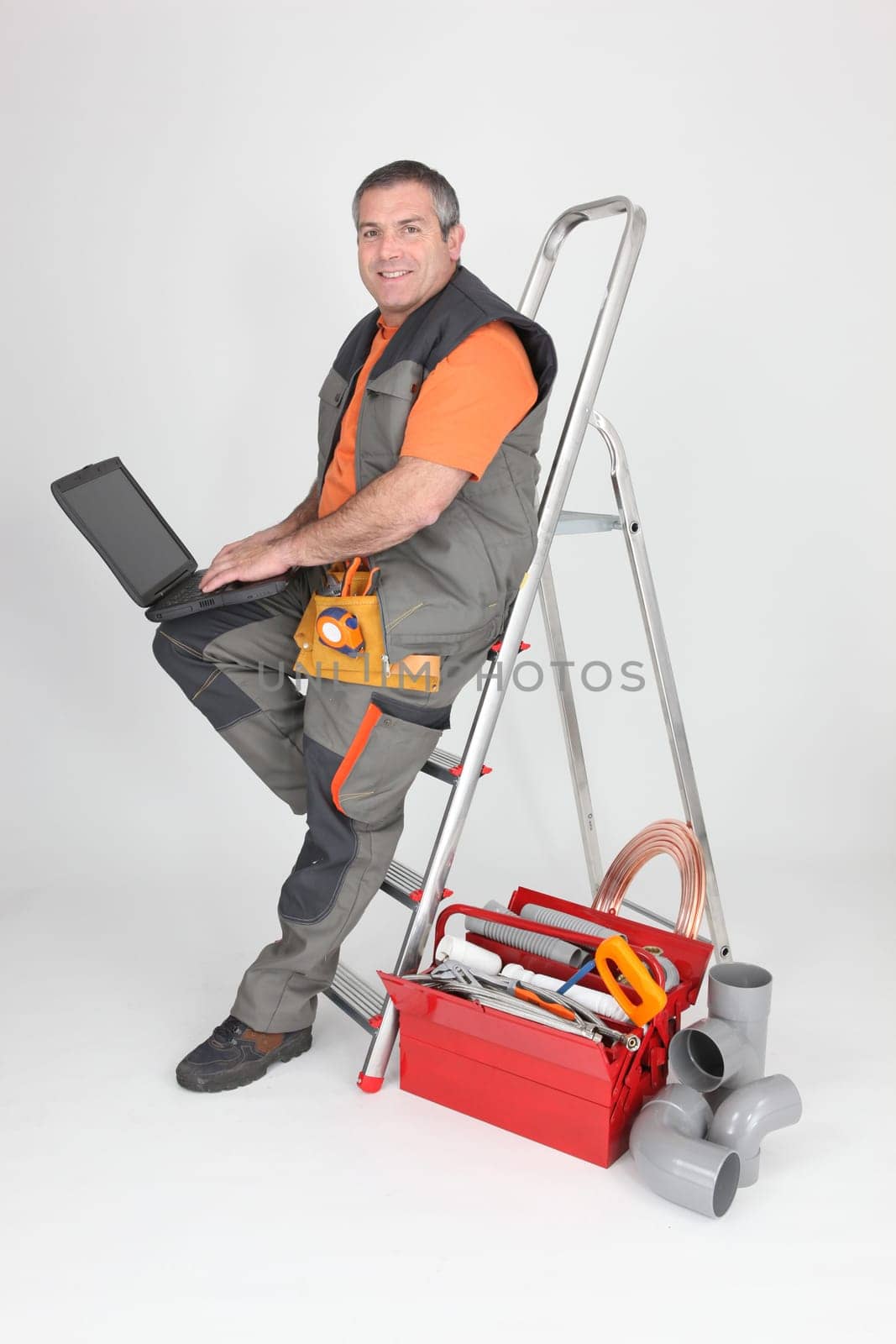 plumber sitting on stepladder with computer