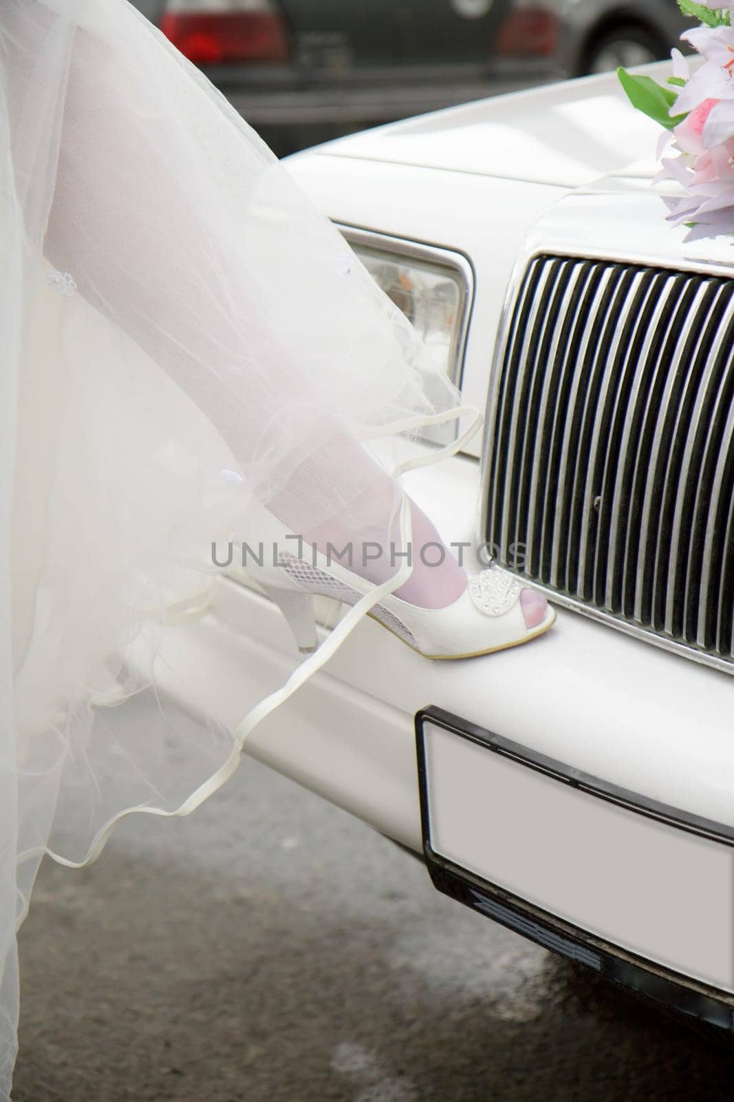 leg of the bride in white shoes on the bumper limousine