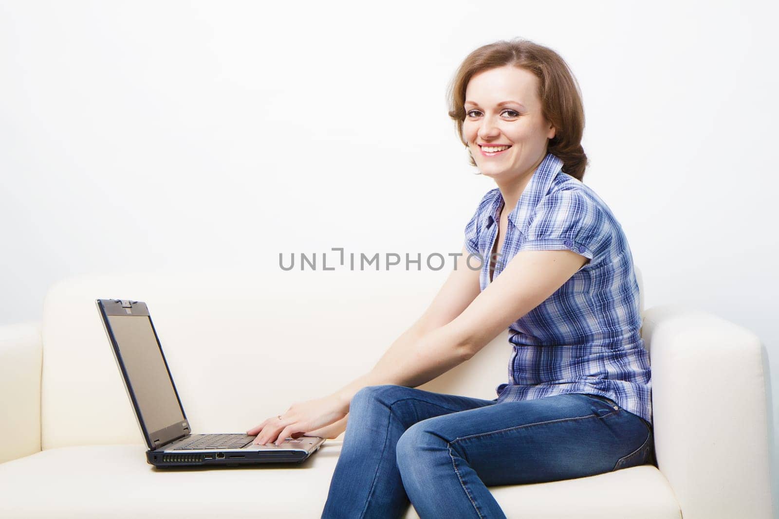 young slender woman with a laptop sitting on the couch