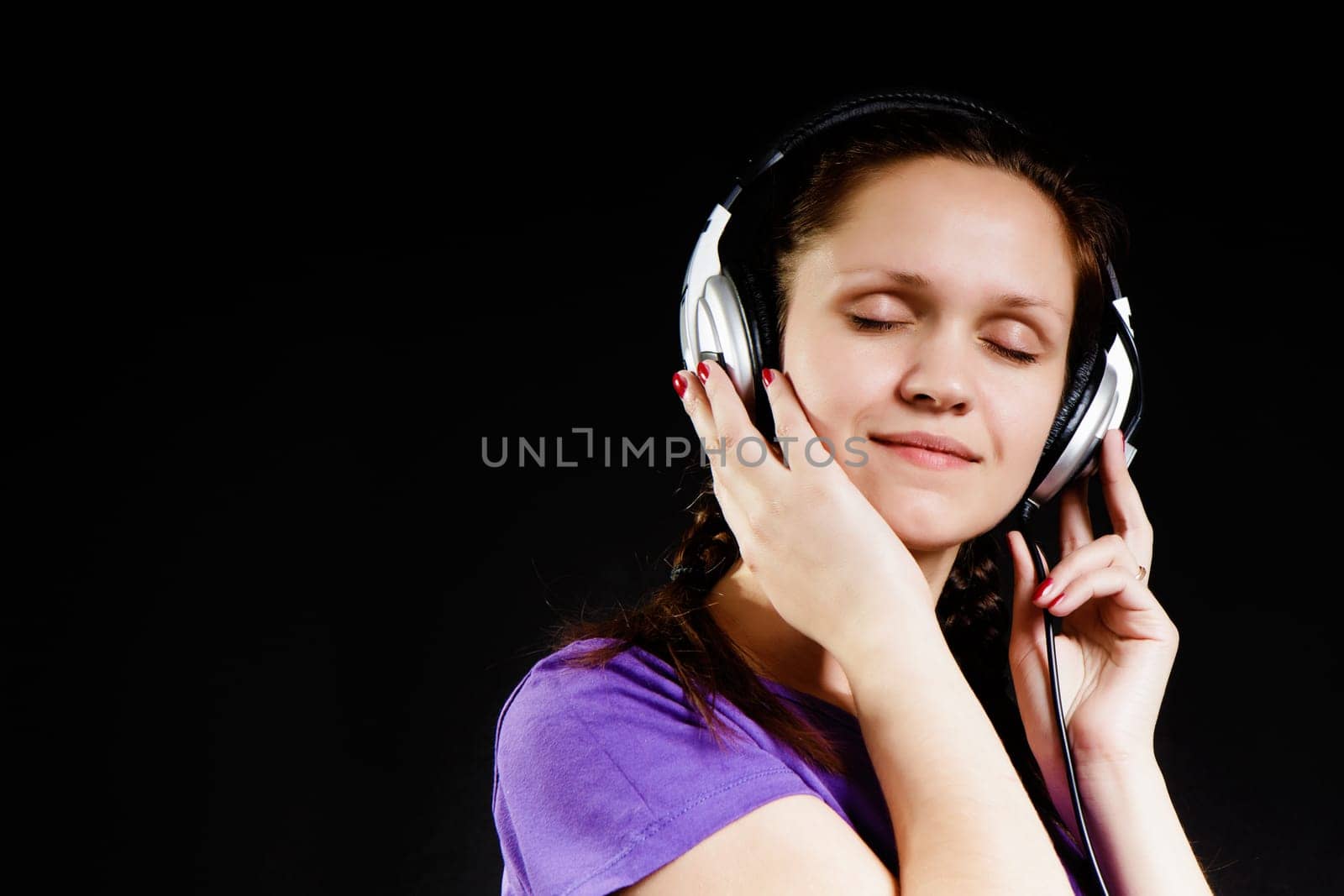 smiling girl with eyes closed in the headphones on a black background